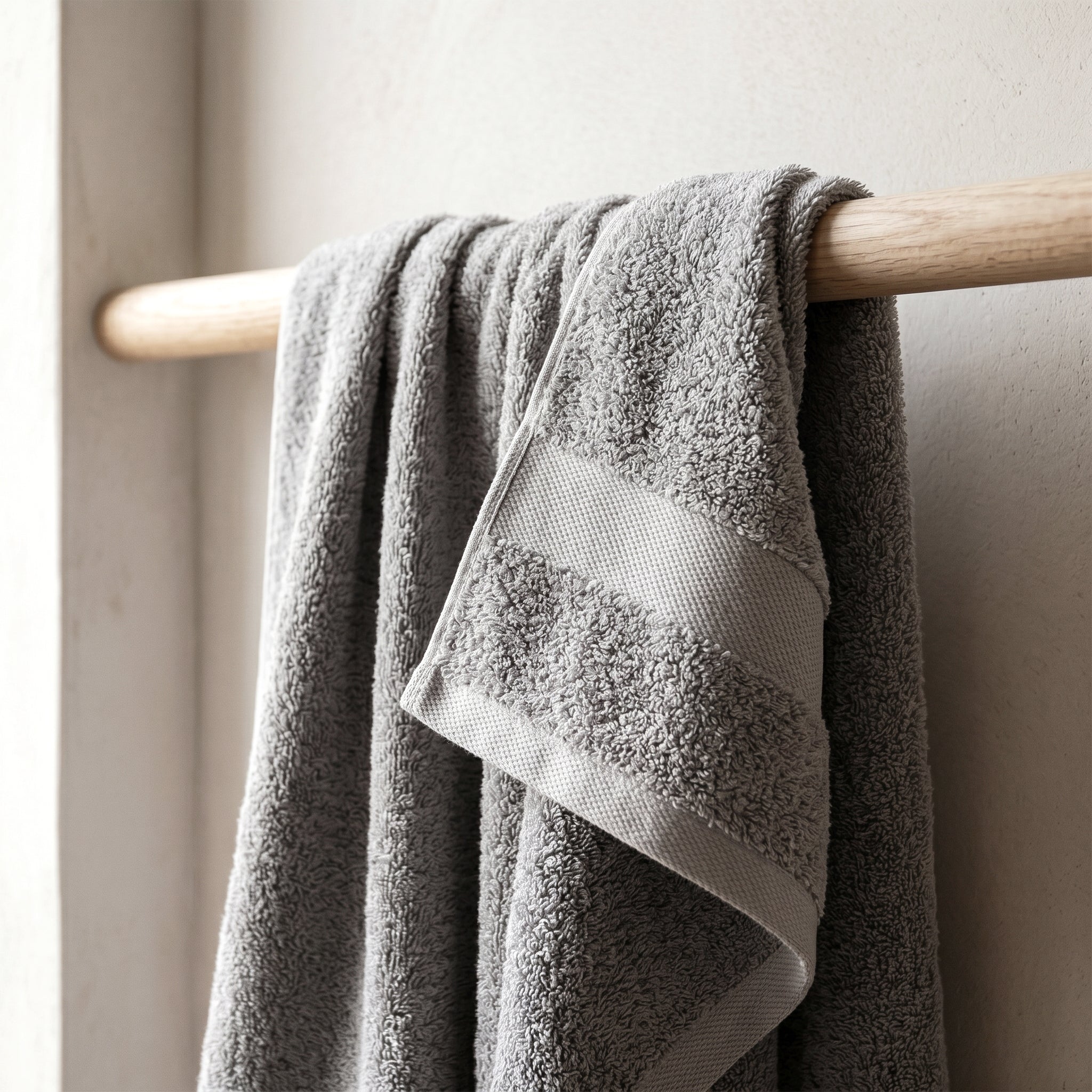 Cotton towel hanging on a wooden rail with visible texture and soft natural light.