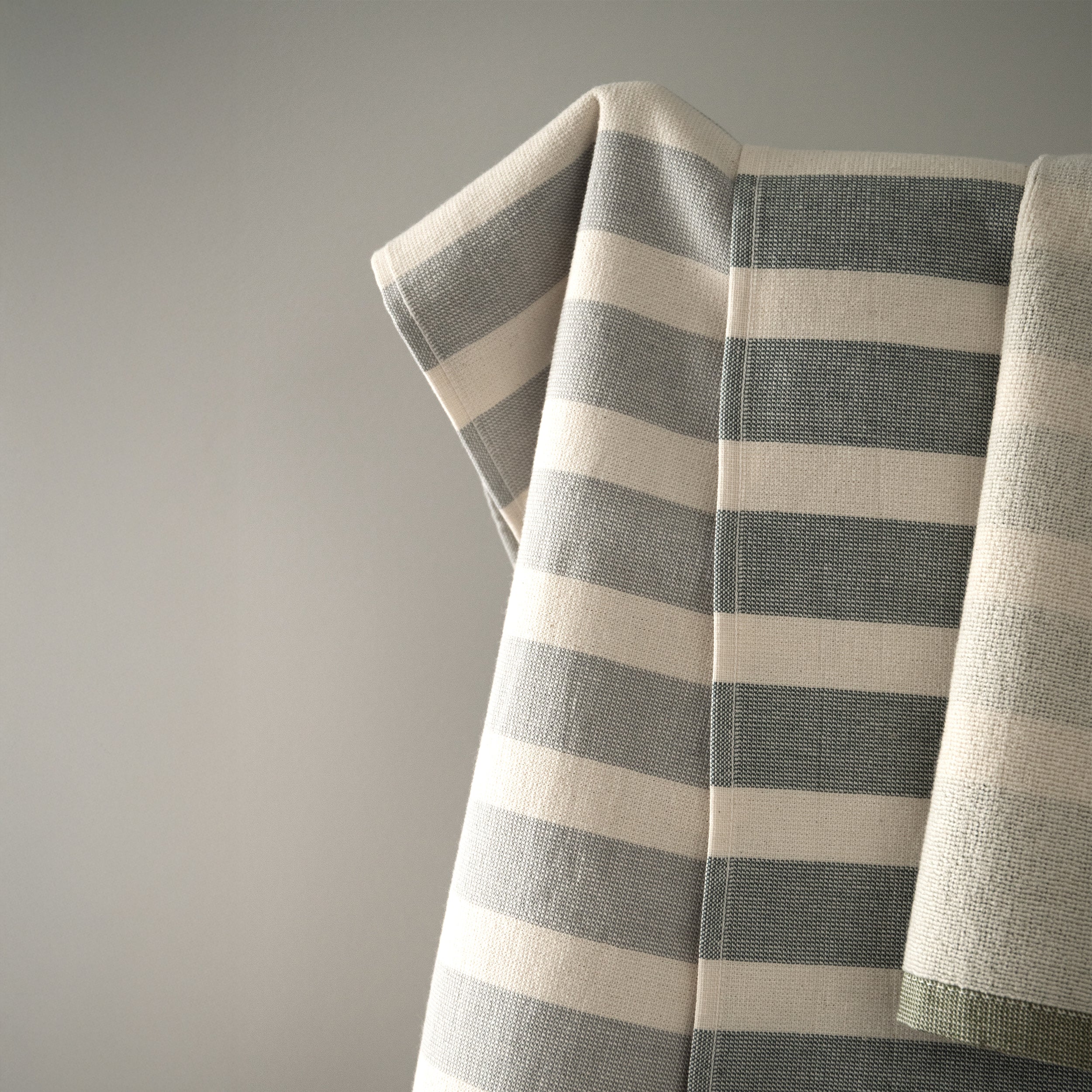 Striped kitchen textiles hanging in soft light with a natural woven texture.