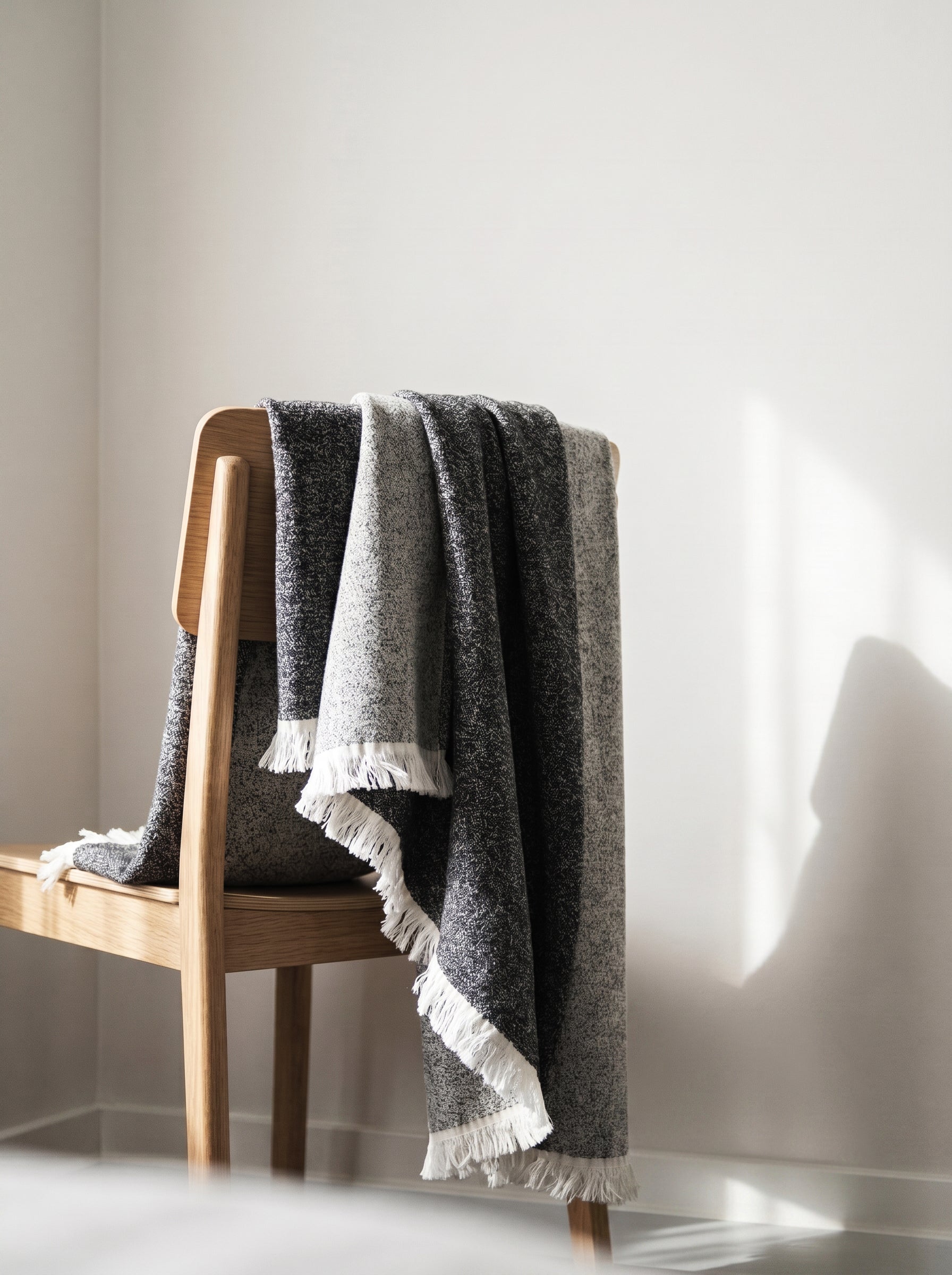Textured cotton throw in grey tones draped over a wooden chair.