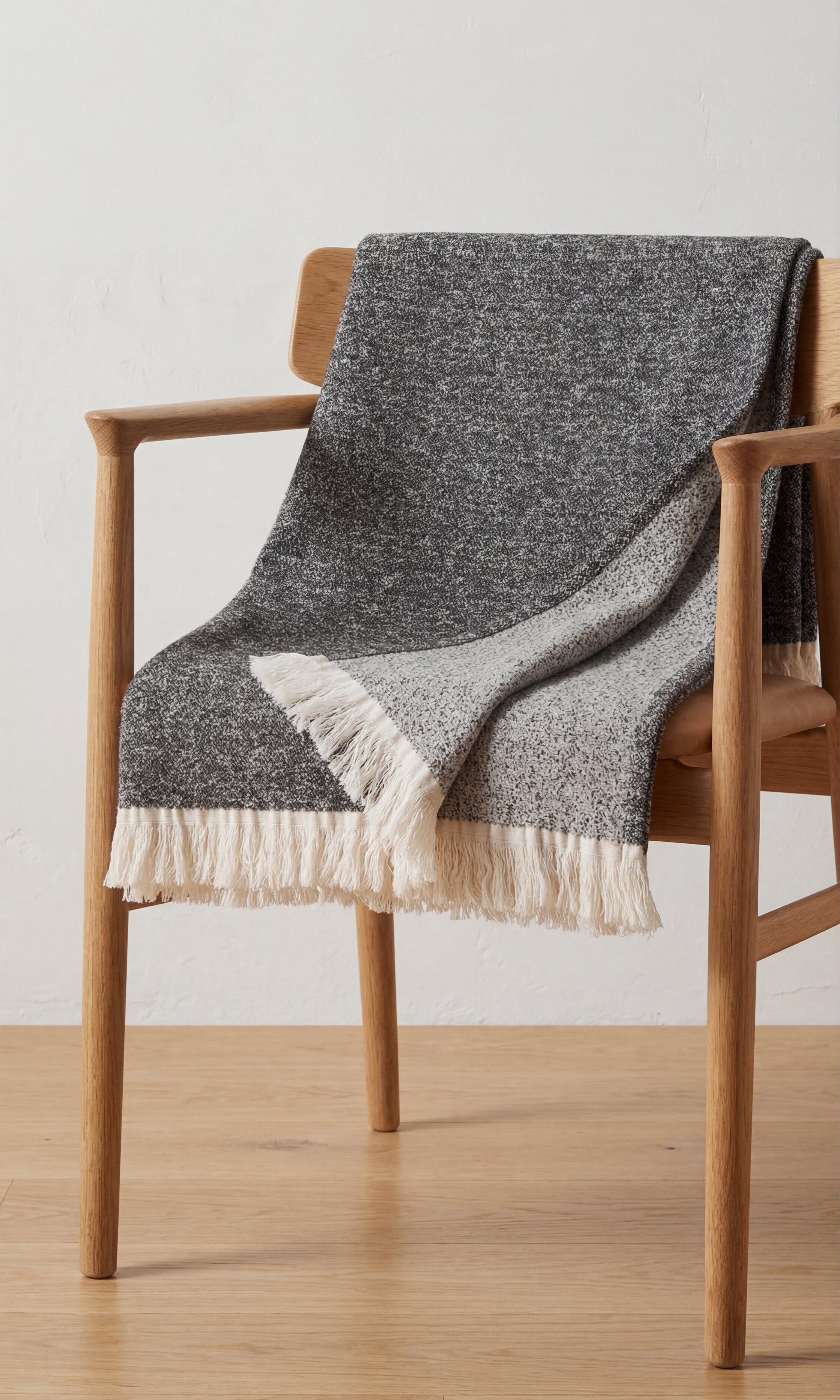 Textured cotton throw in grey tones draped over a wooden chair.