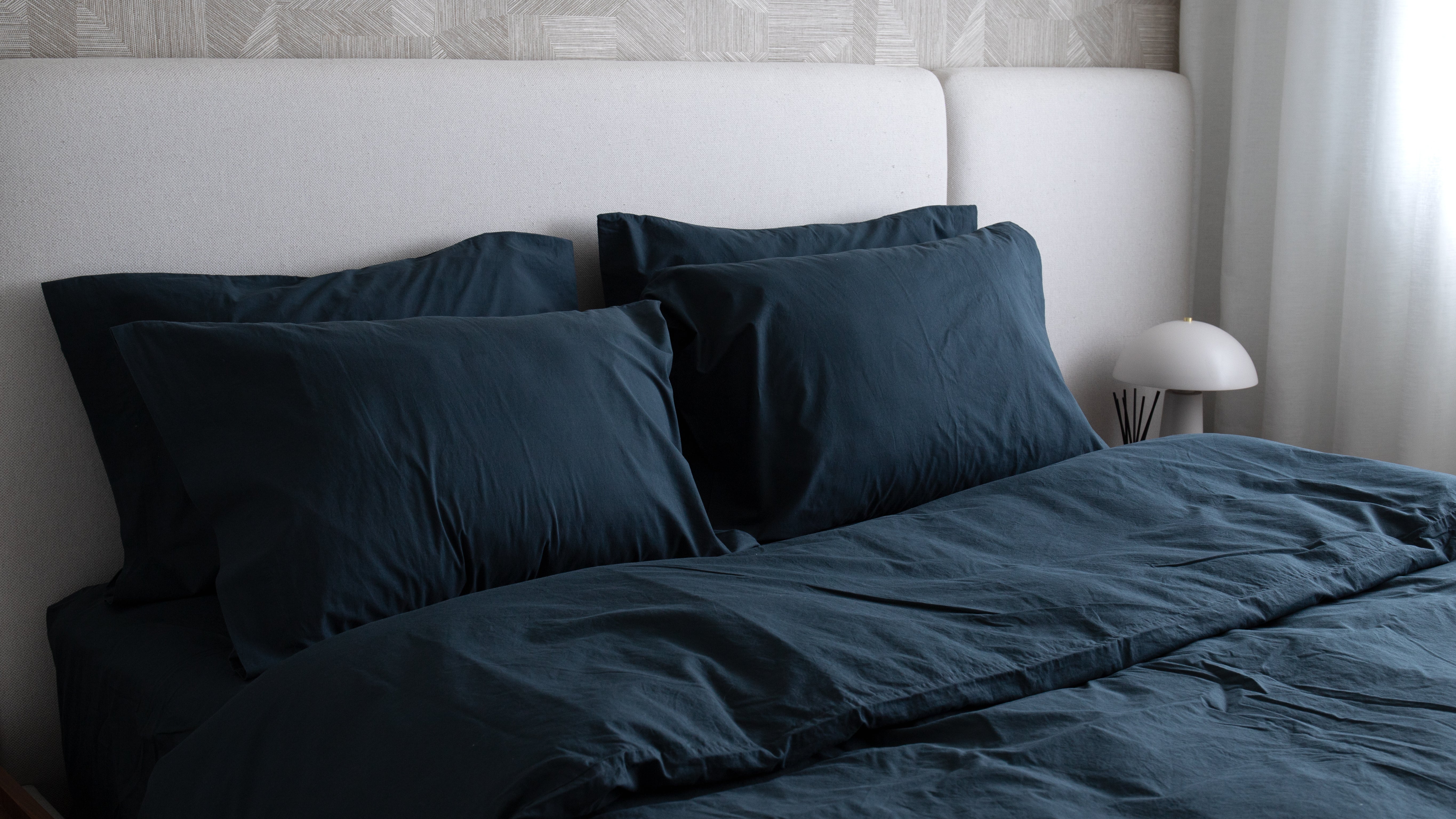 Minimal bedroom with a bed dressed in atlantic blue cotton bedding and matching pillows.