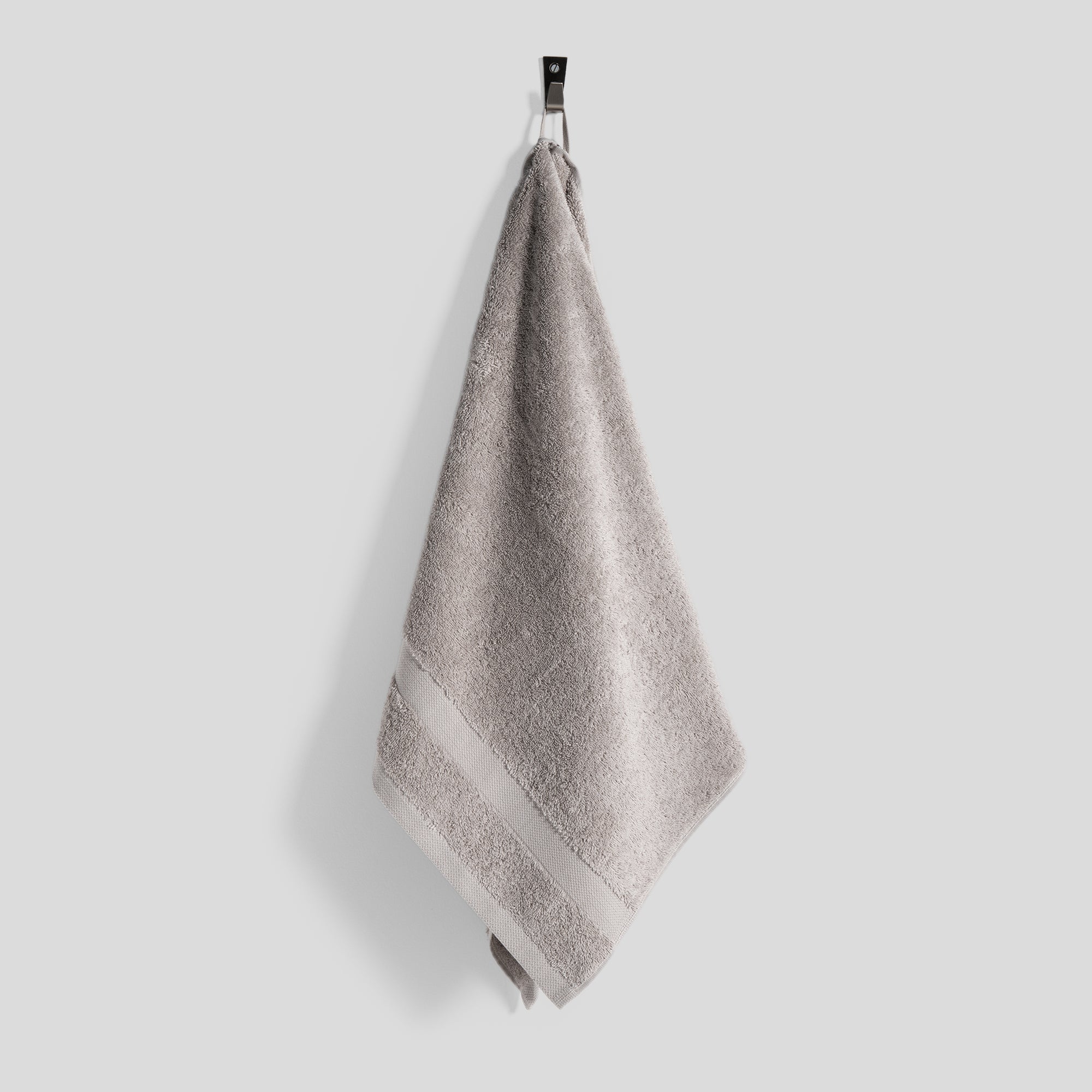 Giza cotton towel hanging on a wall hook with clean and minimal styling.