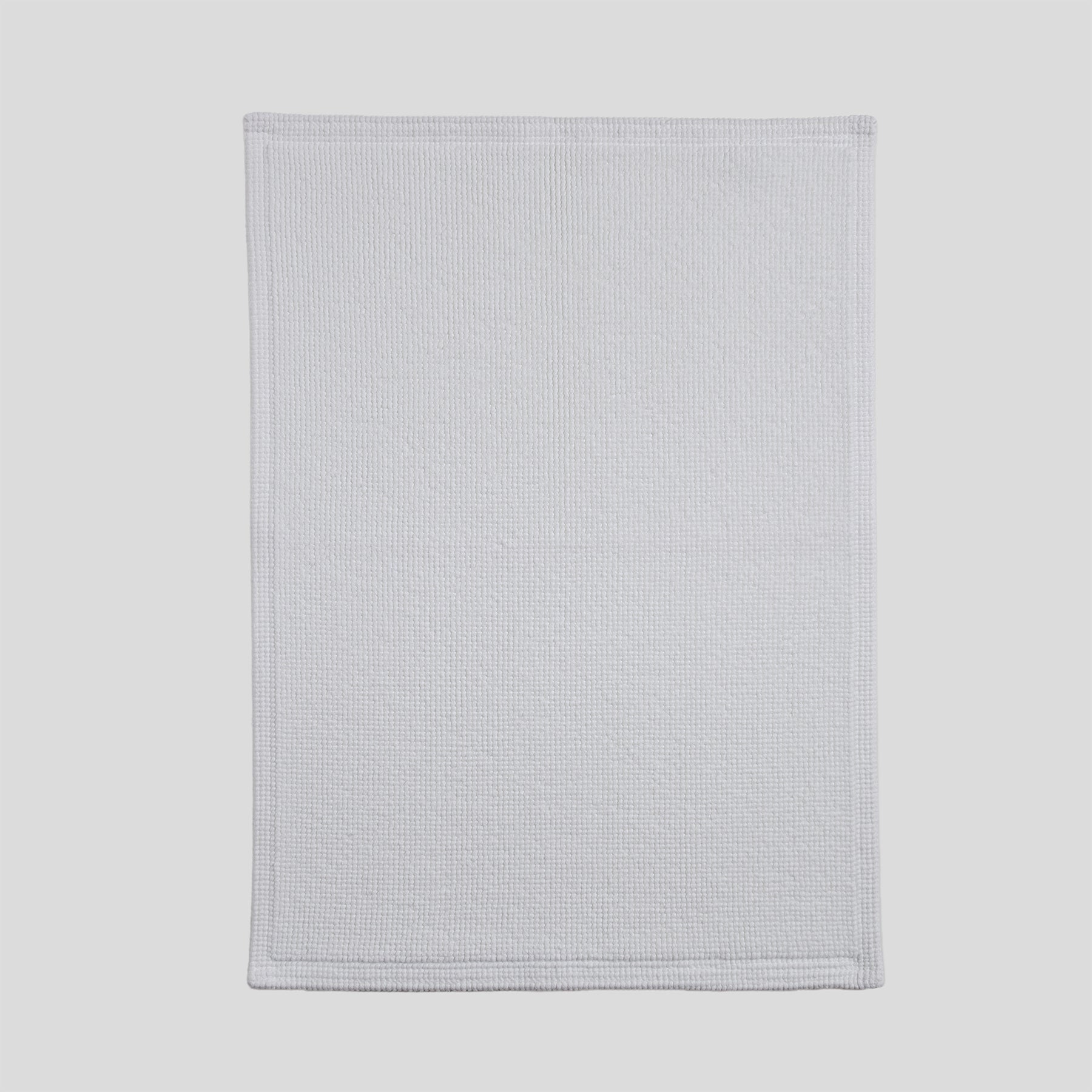 Cotton bath mat in pure white with a dense woven texture and clean edges.