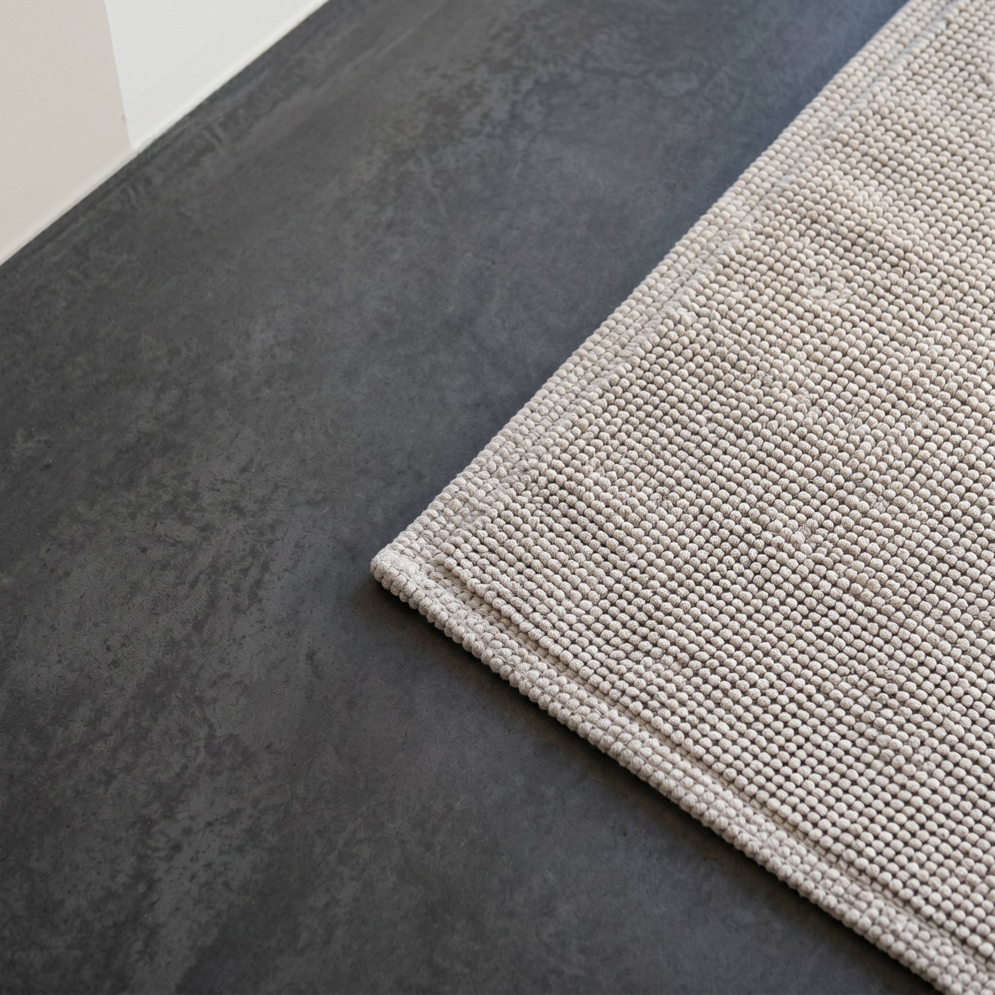 Close-up of a 100% cotton bath mat highlighting its textured weave and neatly finished edges.