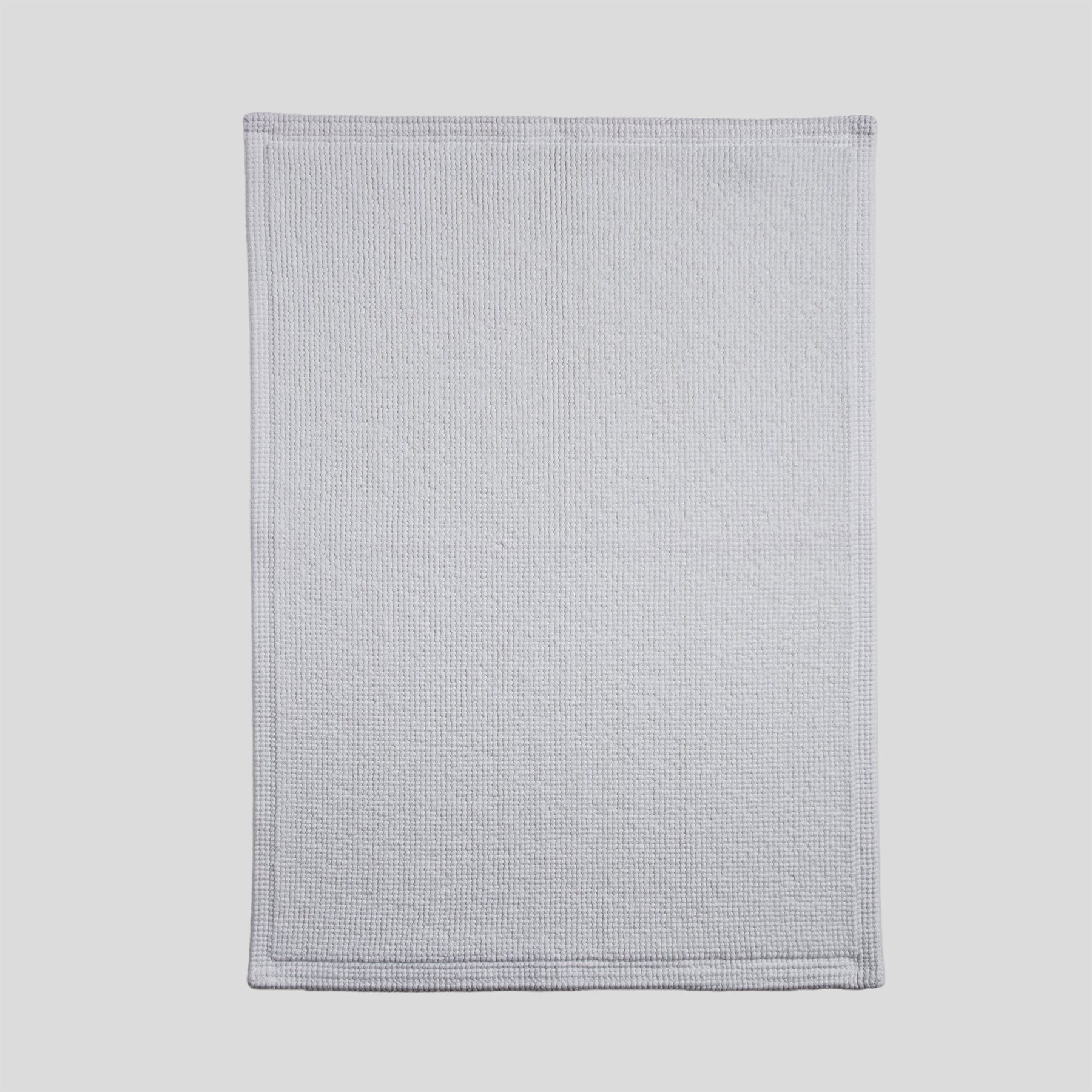 Cotton bath mat in pure white with a dense woven texture and clean edges.