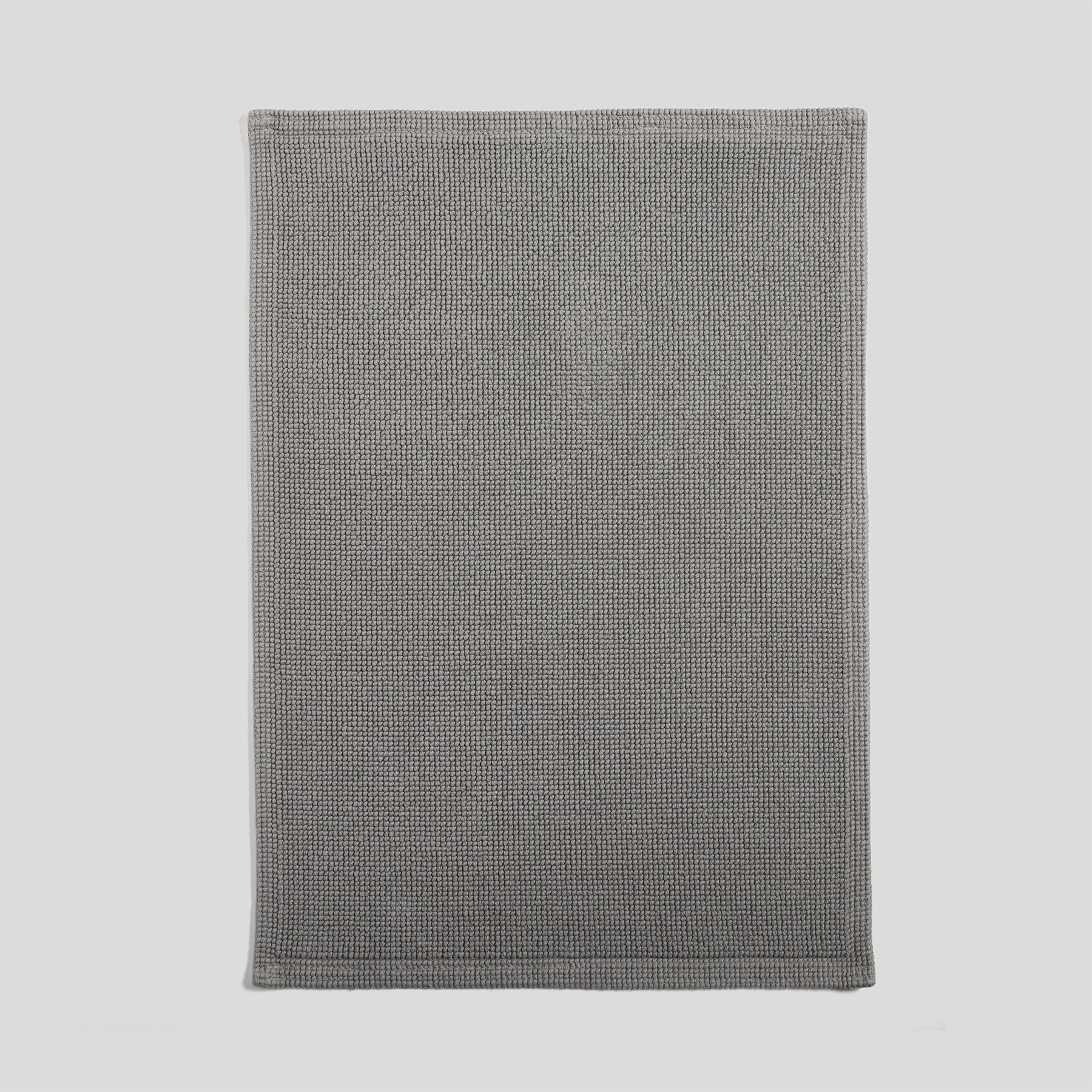 Cotton bath mat in grey with a dense woven texture and clean edges.