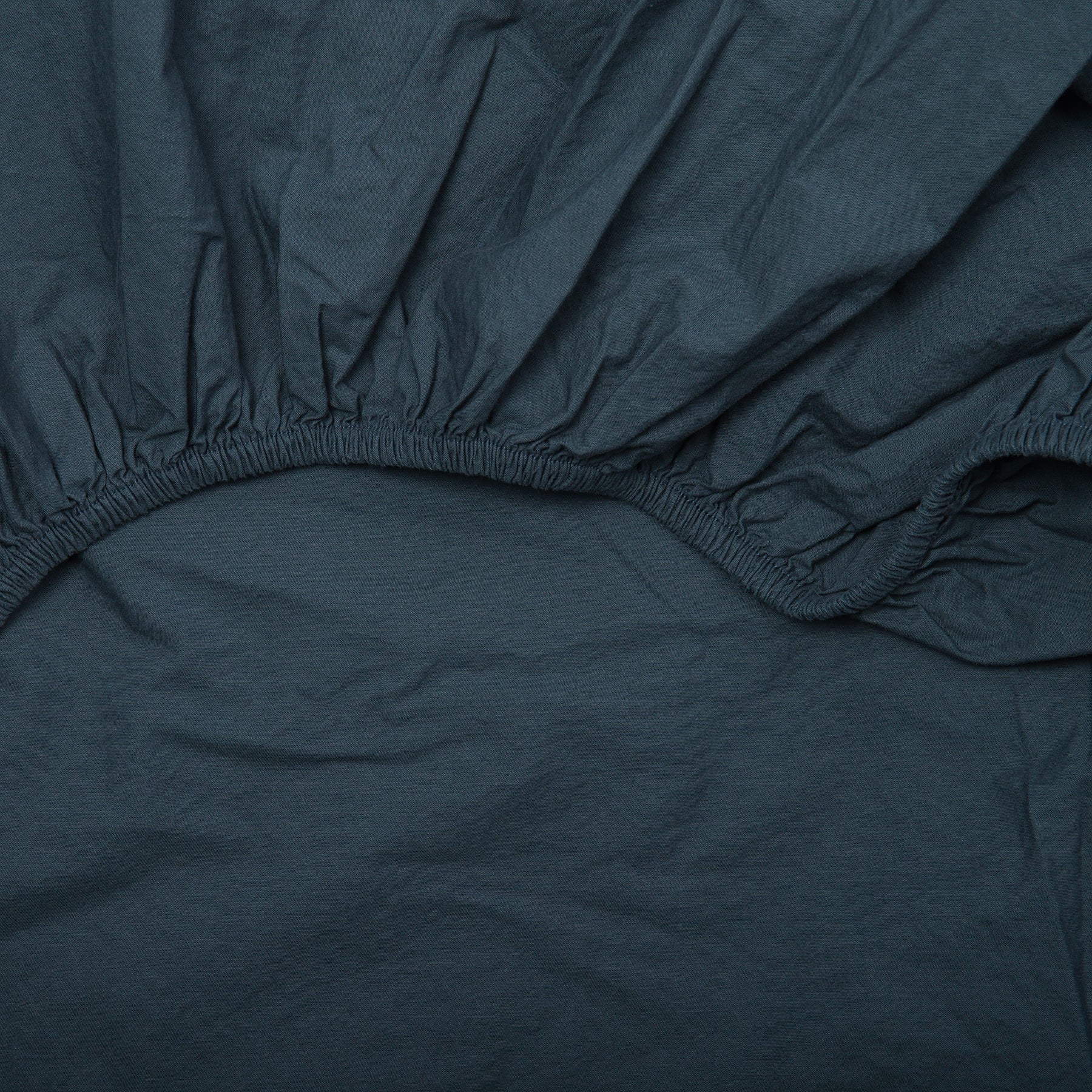 Detail of elastic edge on atlantic blue fitted sheet made from soft certified organic cotton.