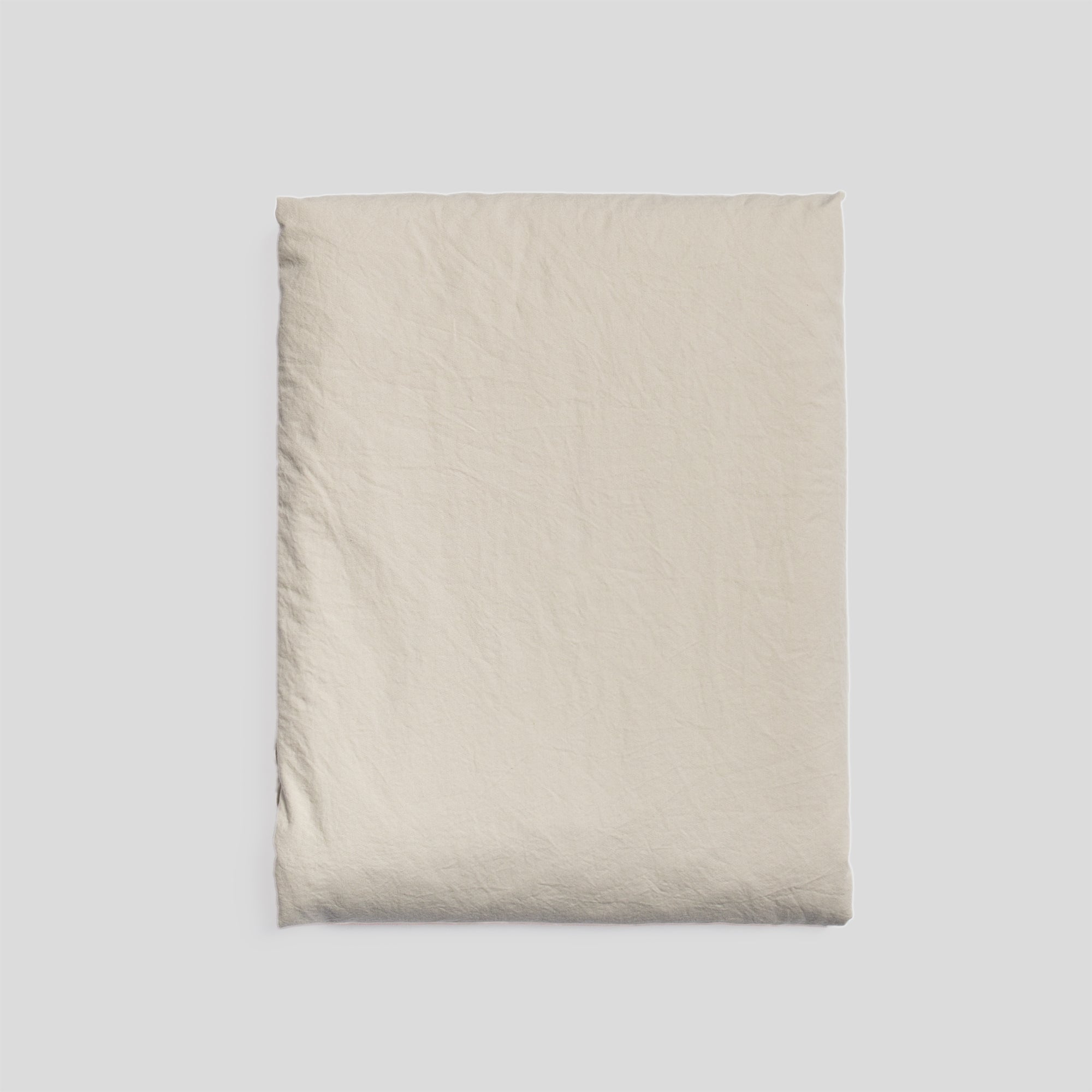 Sand organic cotton fitted sheet folded, ideal for fresh and minimalist bedroom style.
