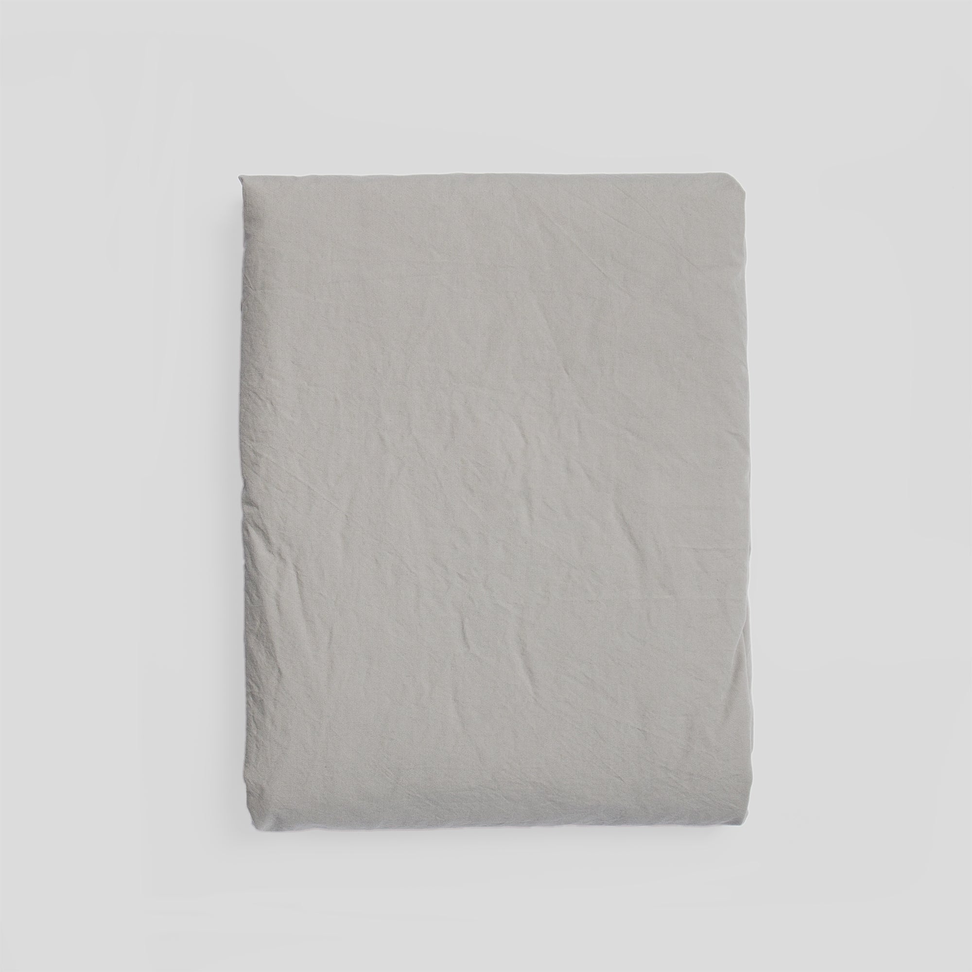 Mist grey organic cotton fitted sheet folded, ideal for fresh and minimalist bedroom style.