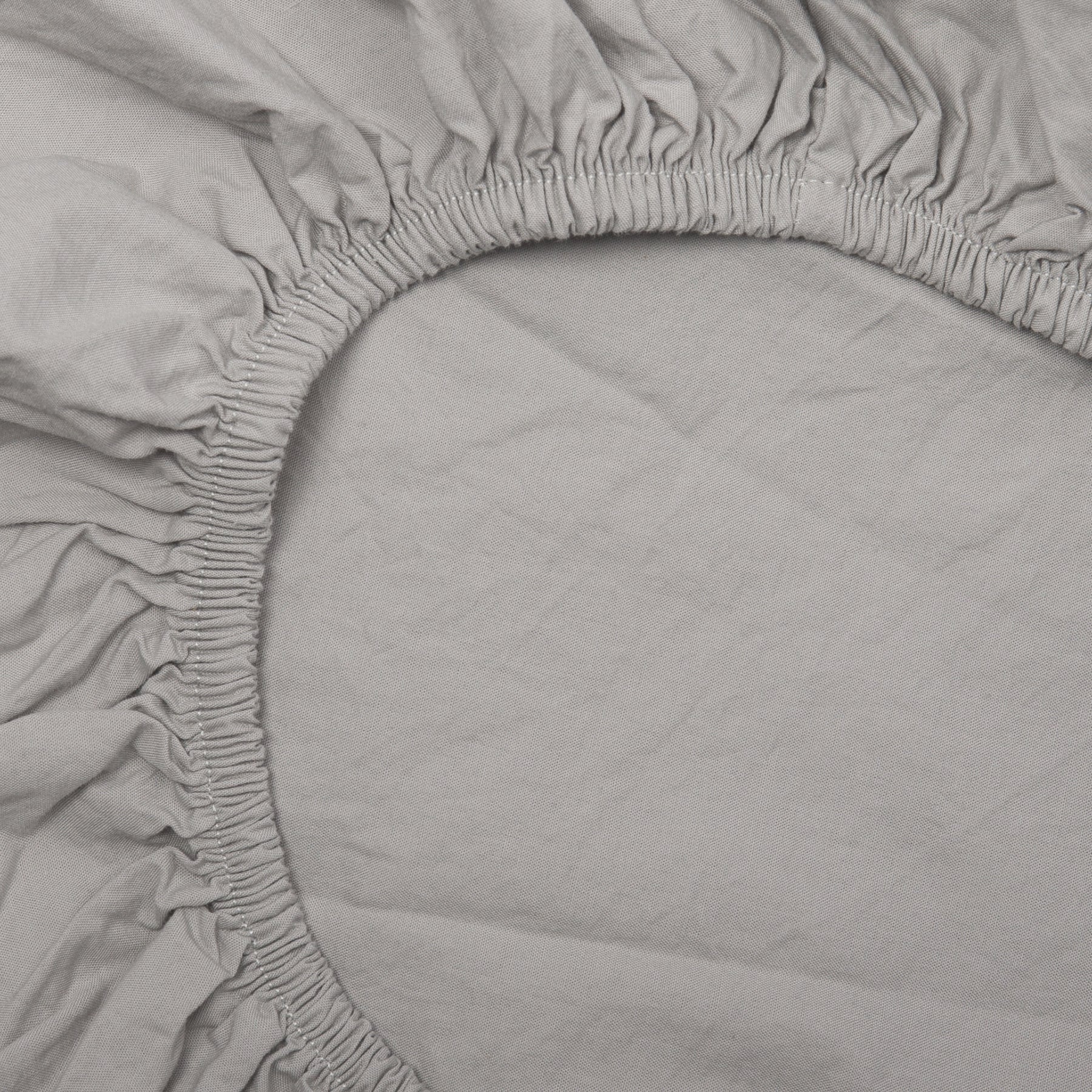 Detail of elastic edge on mist grey fitted sheet made from soft certified organic cotton.
