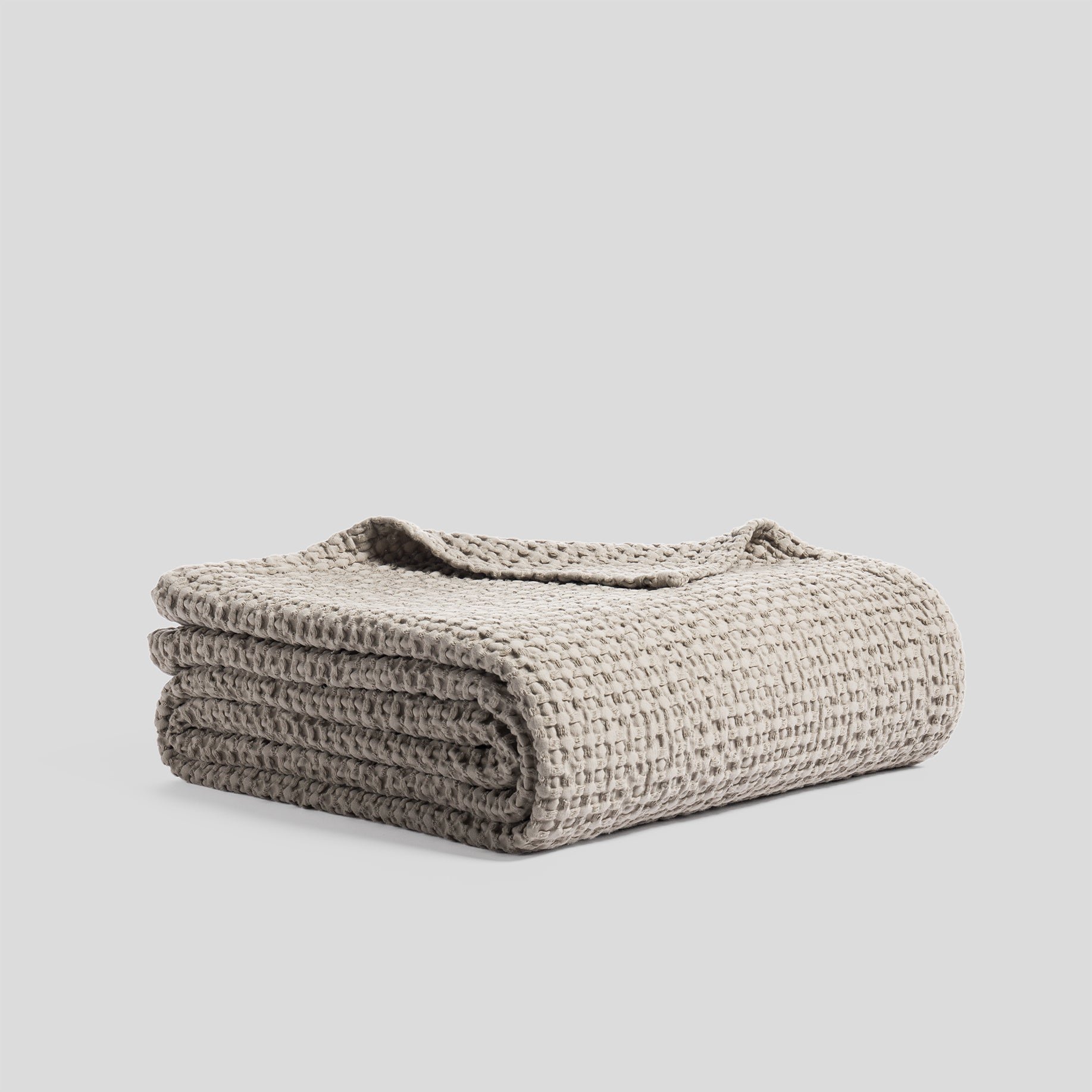 Folded bedspread made of heavy cotton with a waffle texture, in ash color.