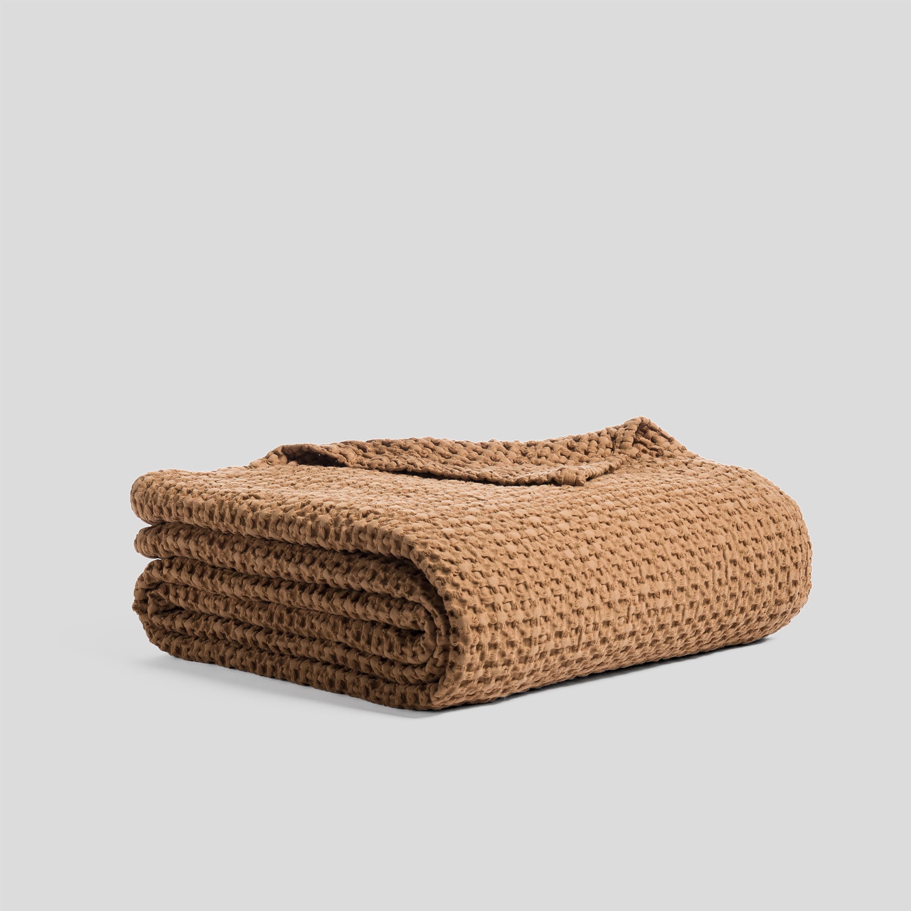Folded bedspread made of heavy cotton with a waffle texture, in clay color.