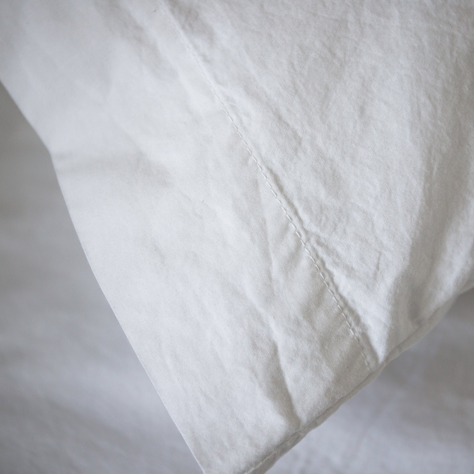 Close-up of a pillowcase seam with soft texture and fine stitching details.