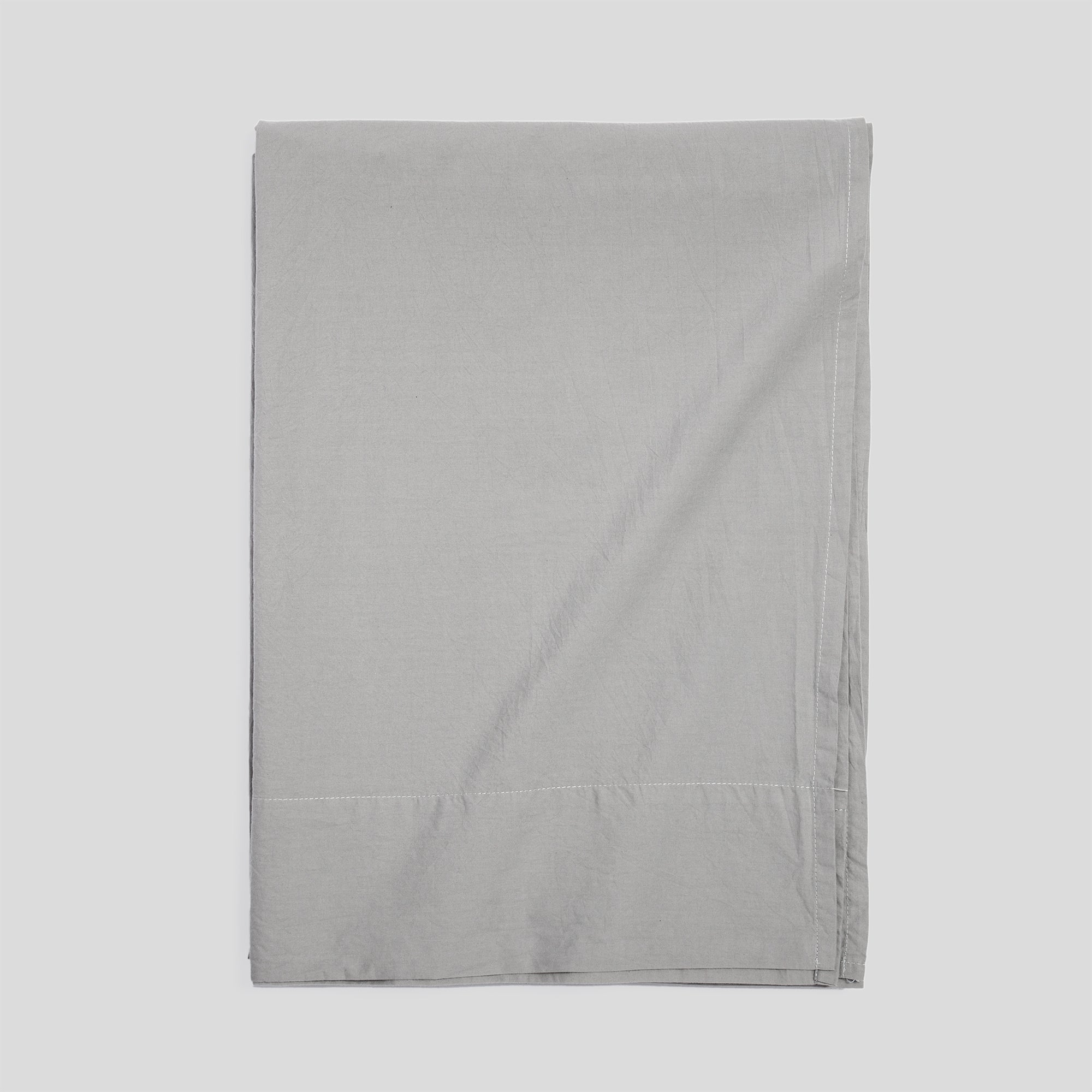 Mist grey flat sheet made of organic cotton, folded for clean, timeless bedroom comfort.