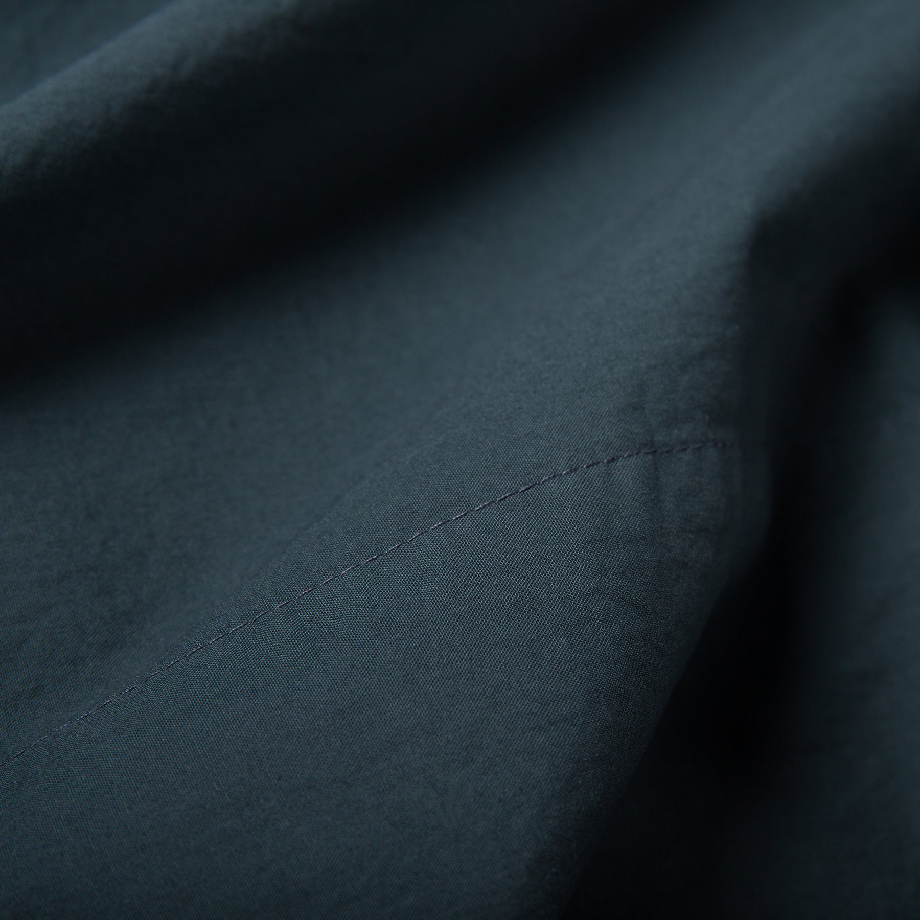 Close-up of atlantic blue organic cotton flat sheet showing soft texture and stitched hemline.