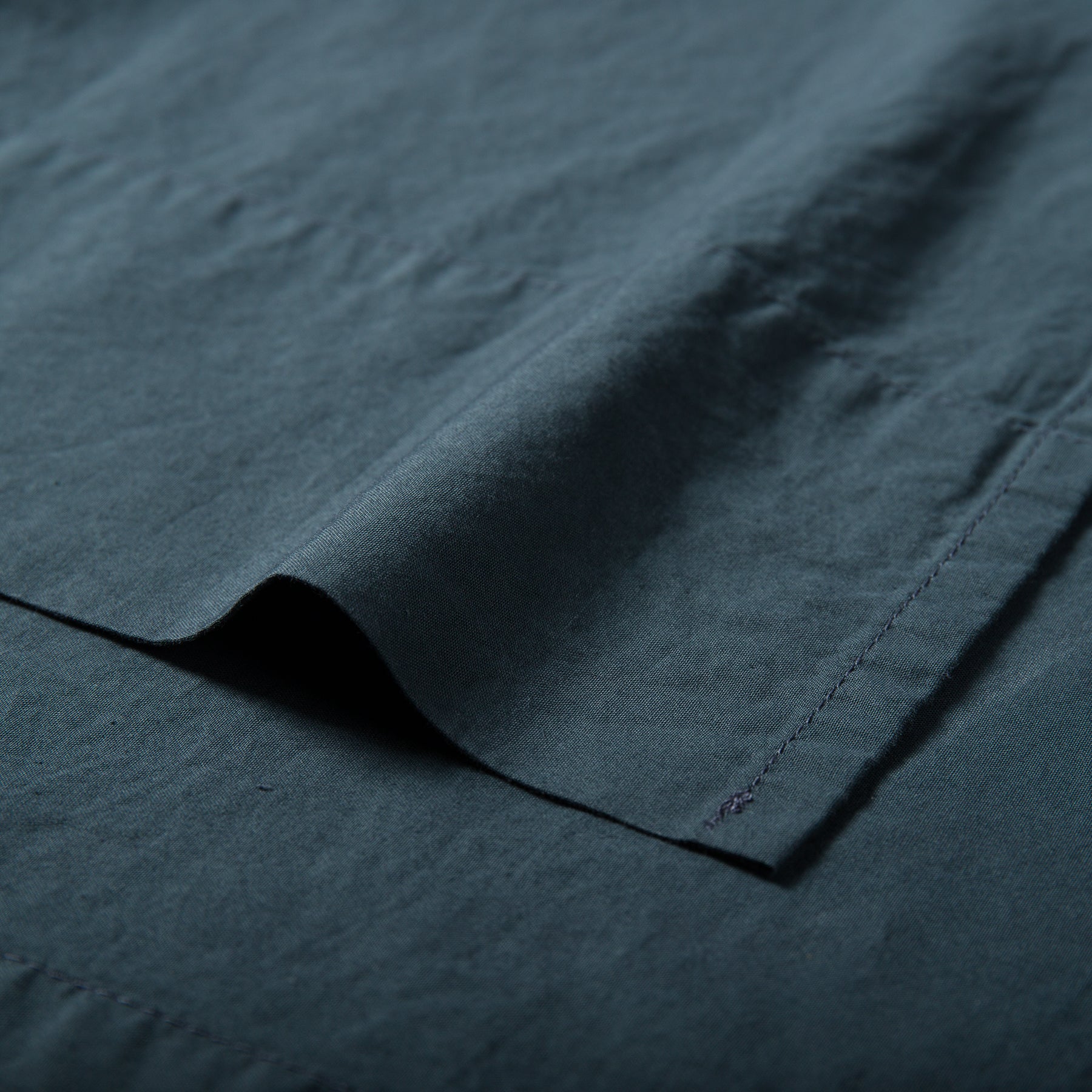 Close-up of atlantic blue organic cotton flat sheet showing soft texture and stitched hemline.