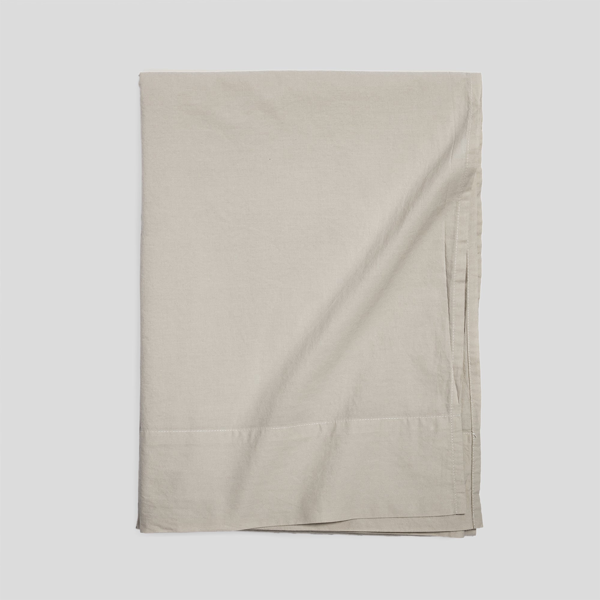 Sand organic cotton flat sheet folded for elegant, breathable and soft bed layering.