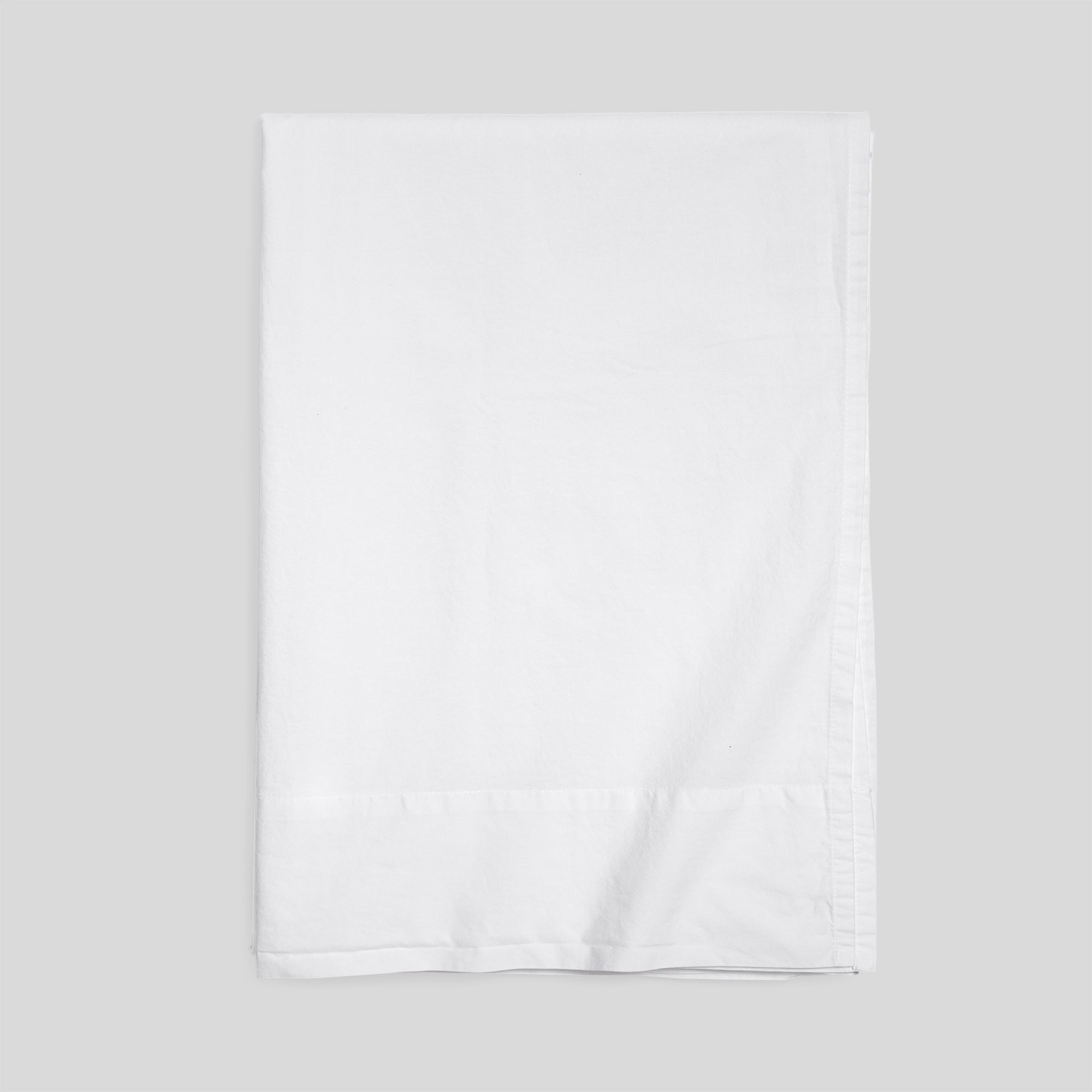 Pure white organic cotton flat sheet folded for elegant, breathable and soft bed layering.