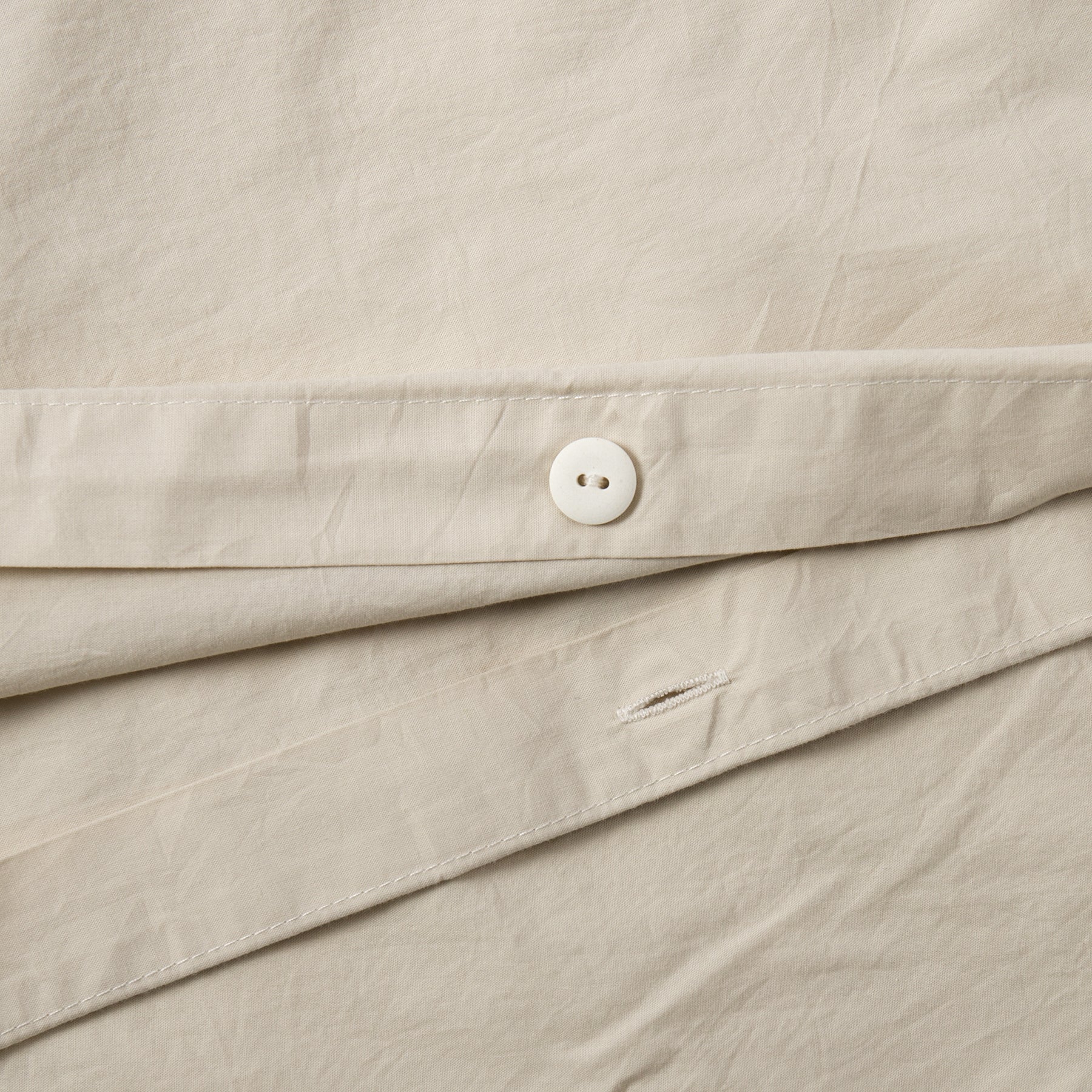 Close-up of button closure on sand organic cotton duvet cover.