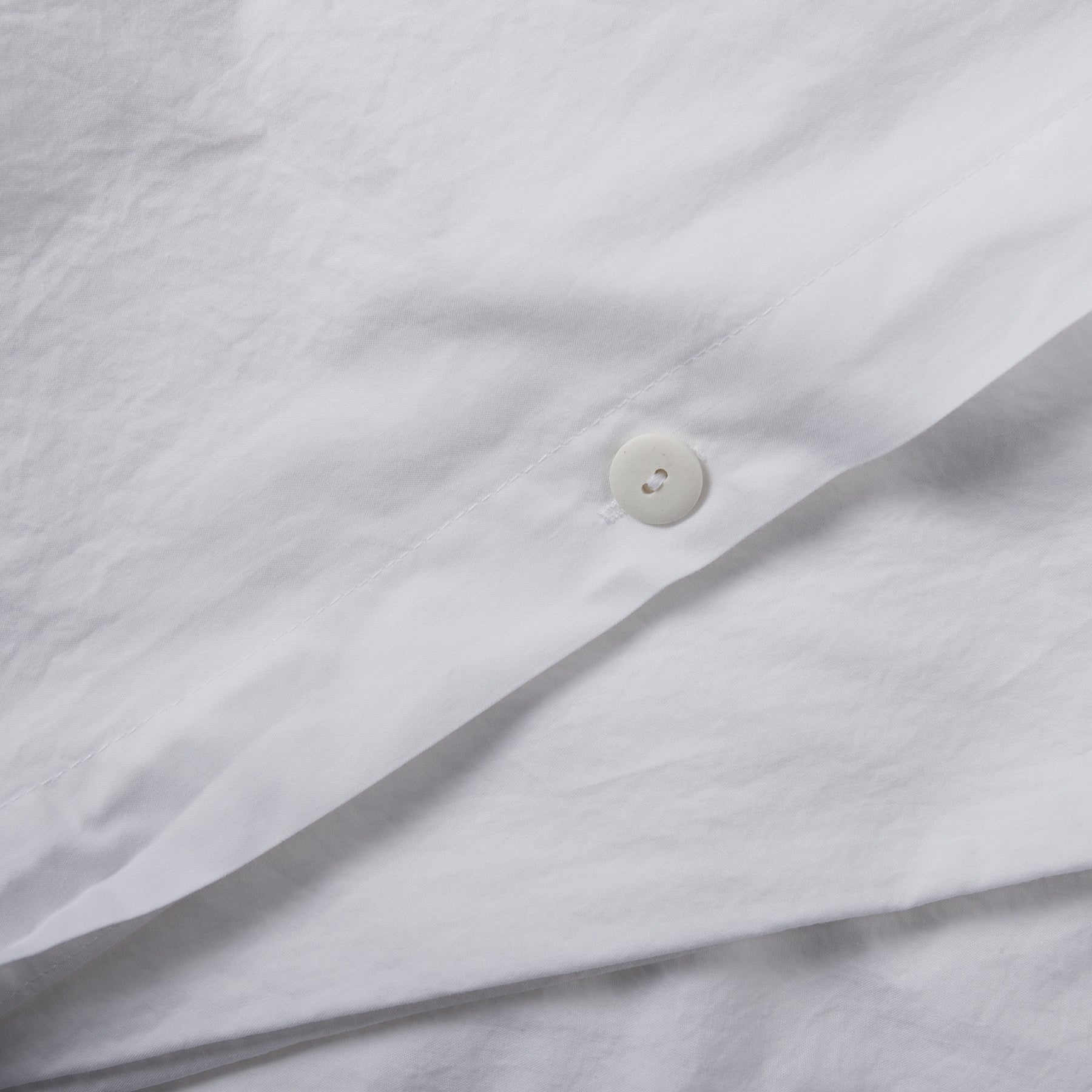 Close-up of button closure on pure white organic cotton duvet cover.