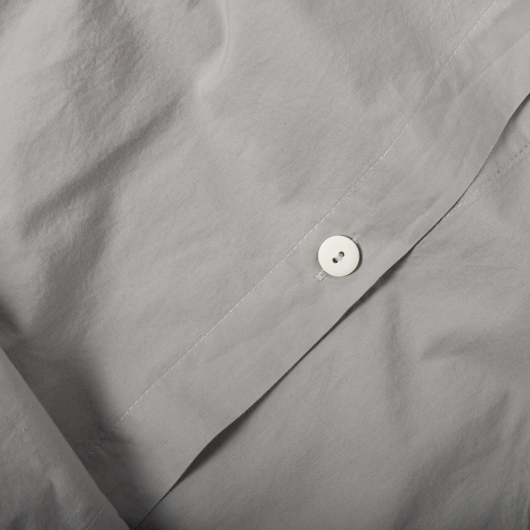 Close-up of button closure on mist grey organic cotton duvet cover.