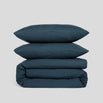 Duvet cover set in atlantic blue, including two stacked pillowcases and a folded duvet cover, made of organic cotton.