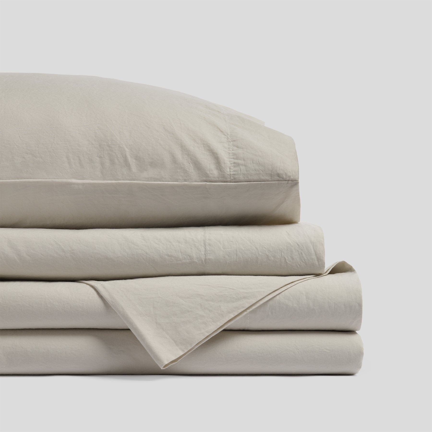 Folded organic cotton sheet set in sand with a smooth finish and soft fabric texture.