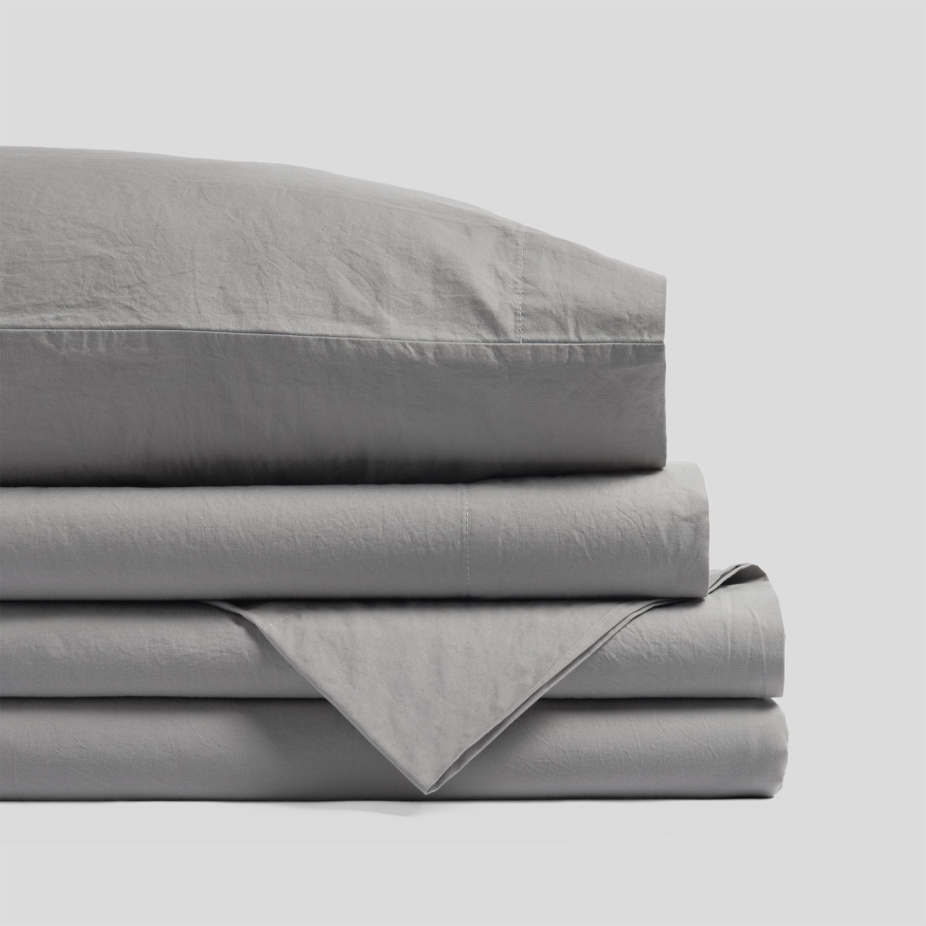 Folded organic cotton sheet set in mist grey with a smooth finish and soft fabric texture.