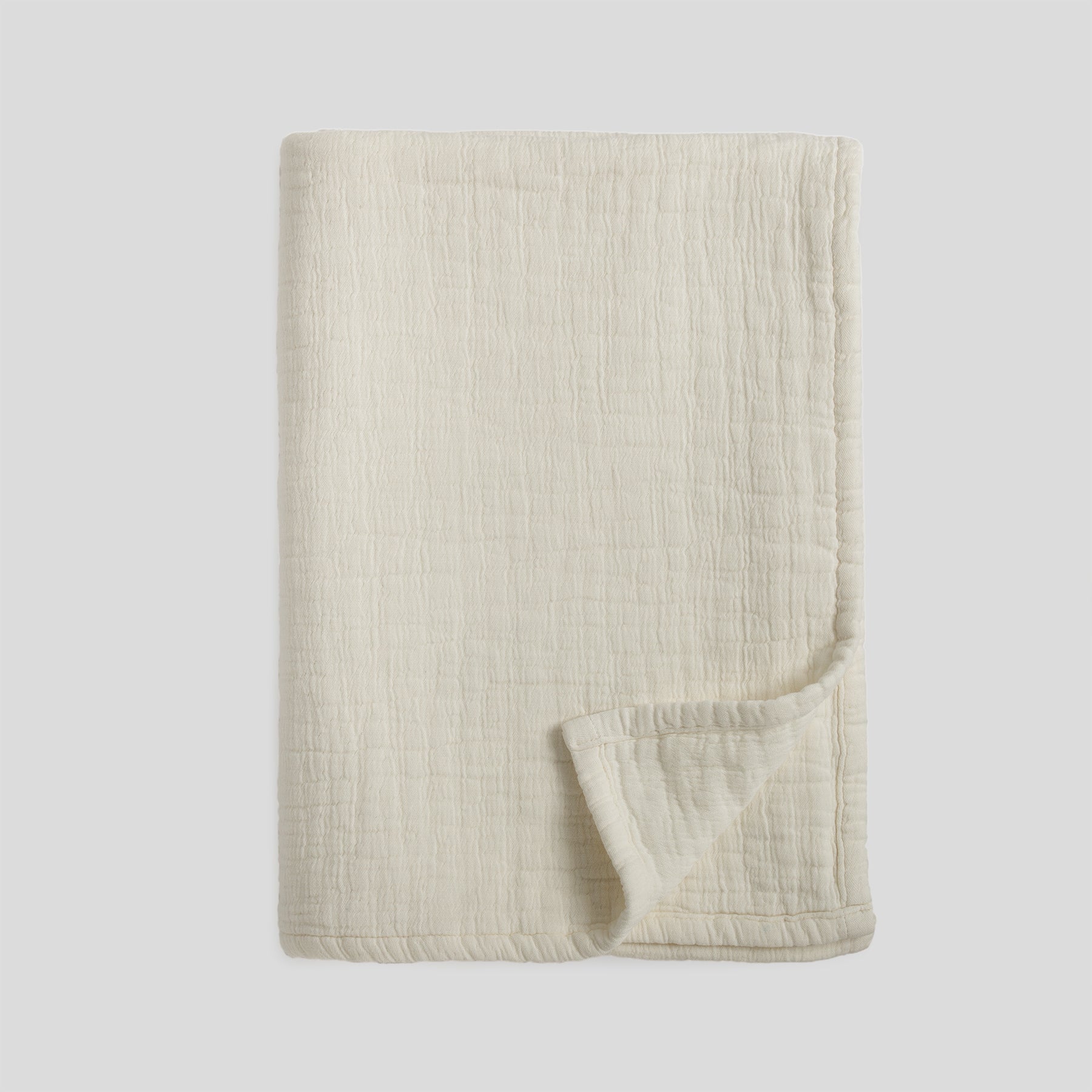 Folded soft cotton muslin blanket in snow color with a lightly textured surface.