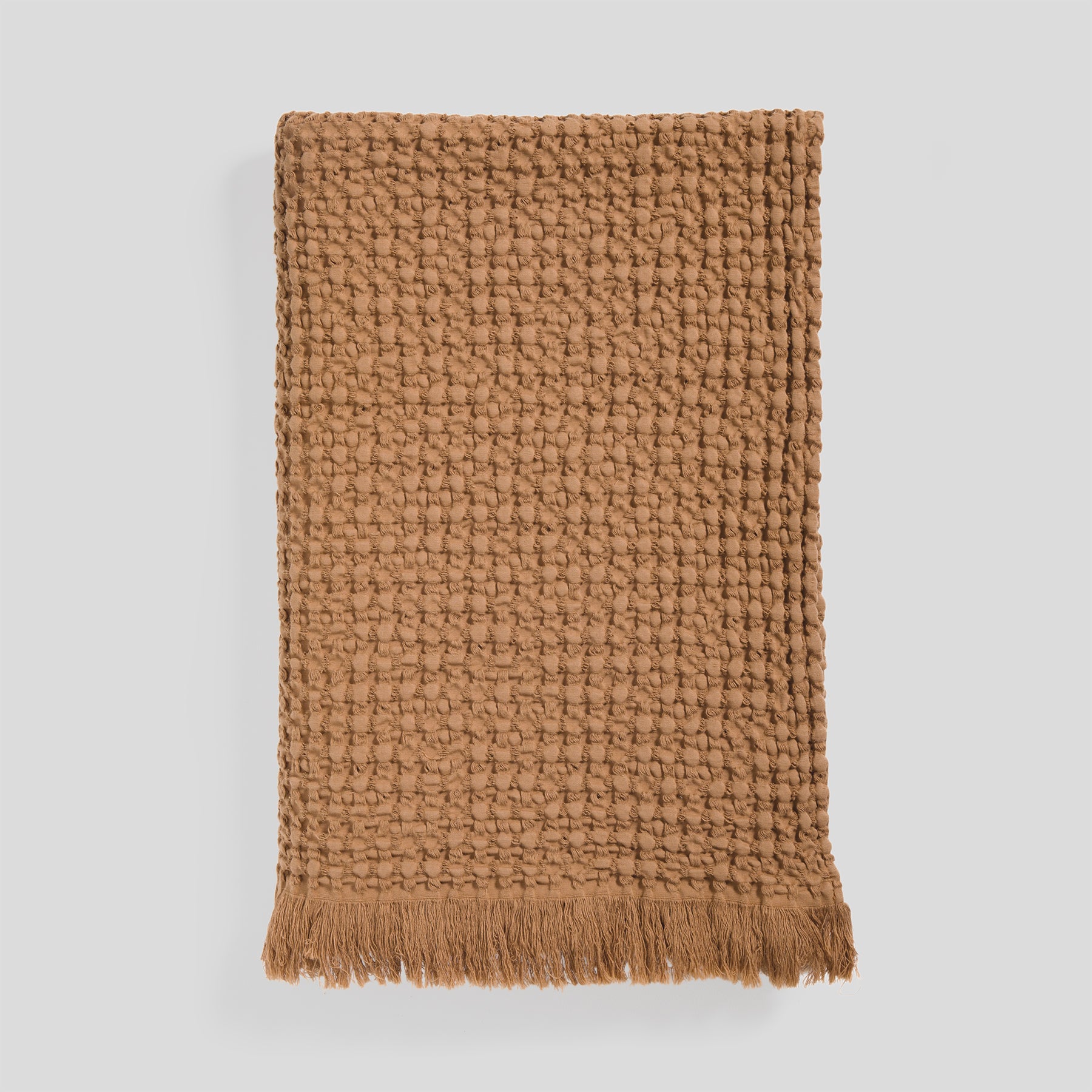 Cotton blanket in clay with a soft waffle surface and fringed edge detail.