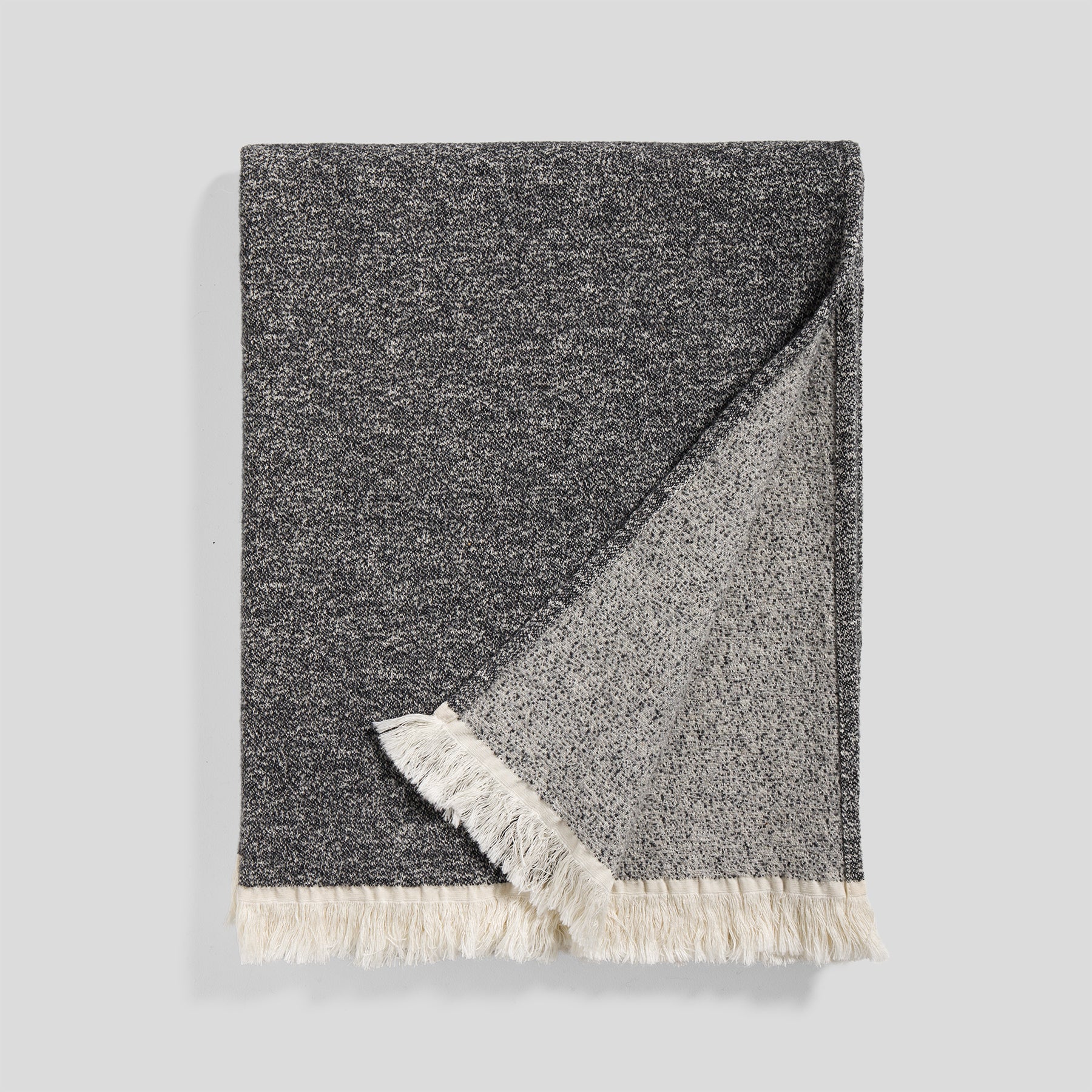 Soft wool and cotton blanket in ash color with a textured weave and fringed edge.