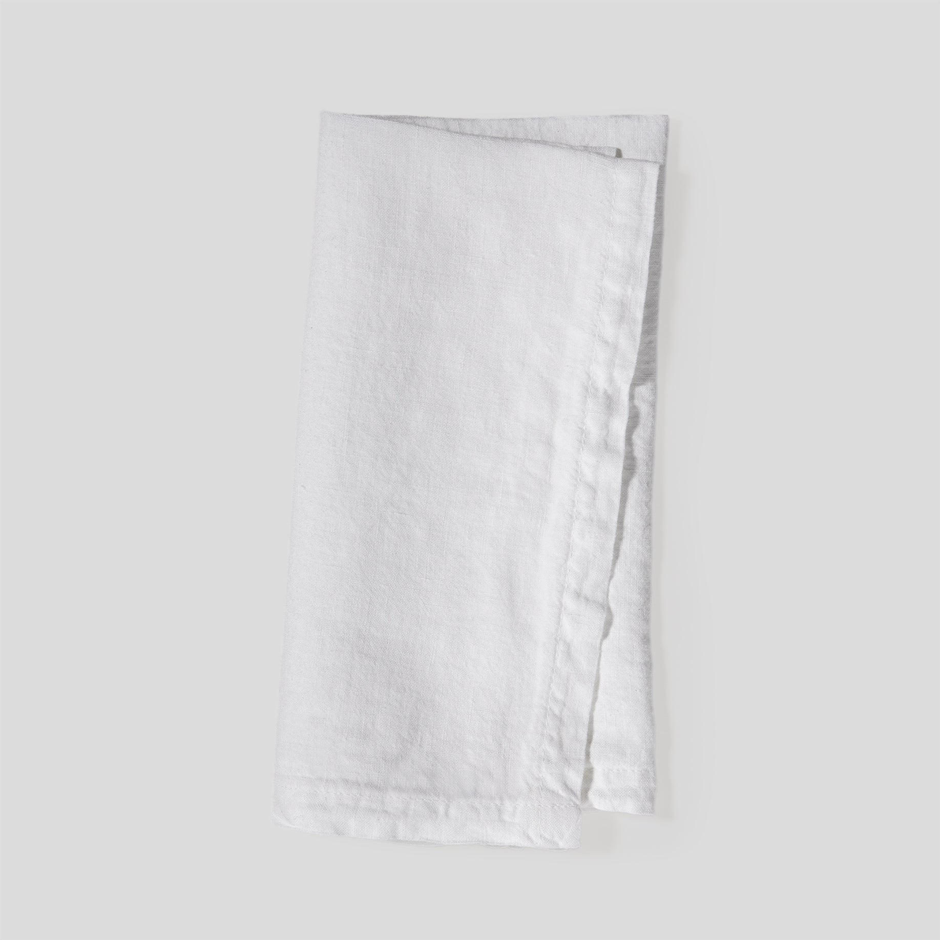 Folded light linen napkins in pure white with a smooth, natural fabric texture.