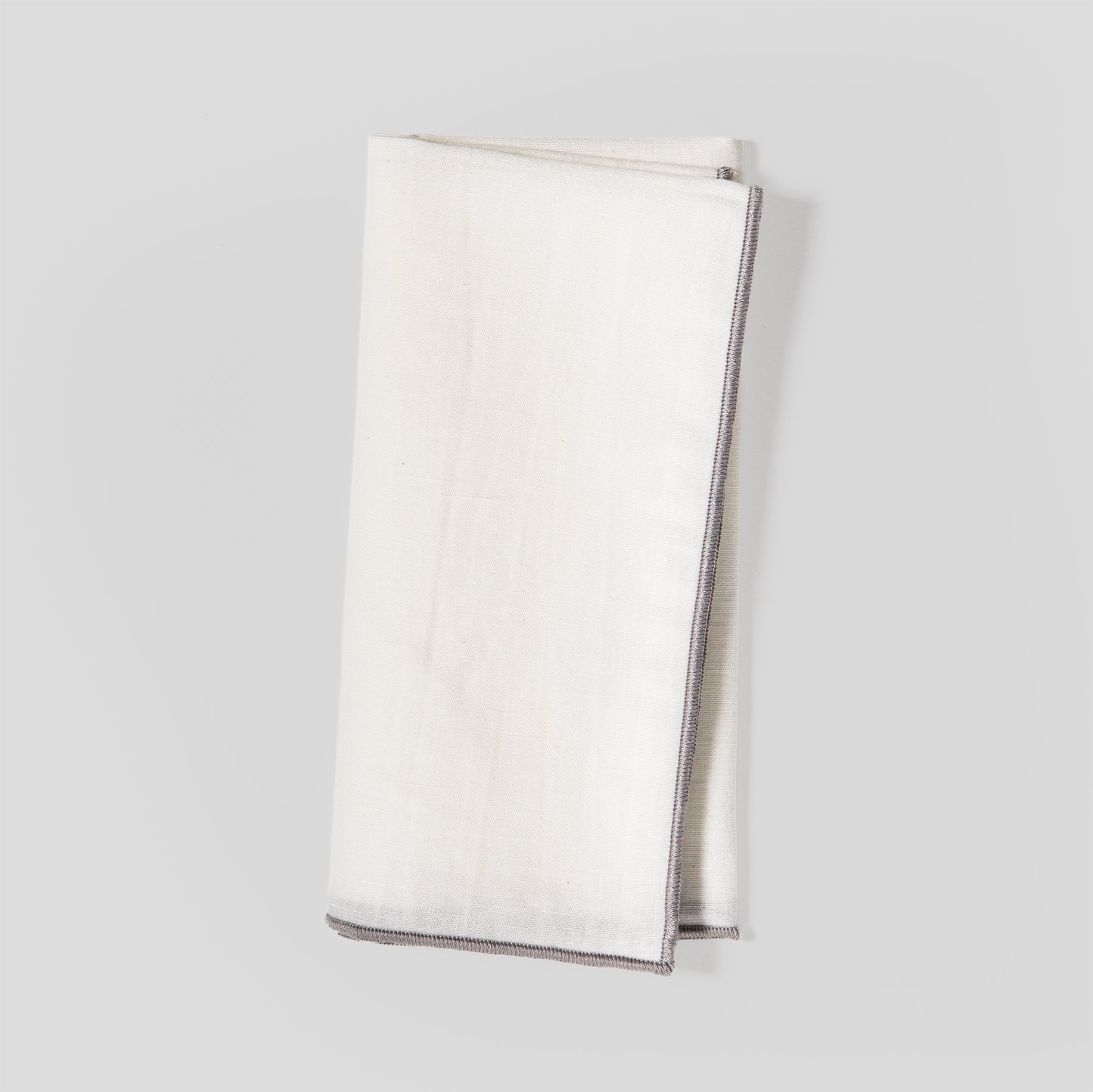 Folded linen and cotton napkins showing a natural fabric texture and grey overlock edge detail.