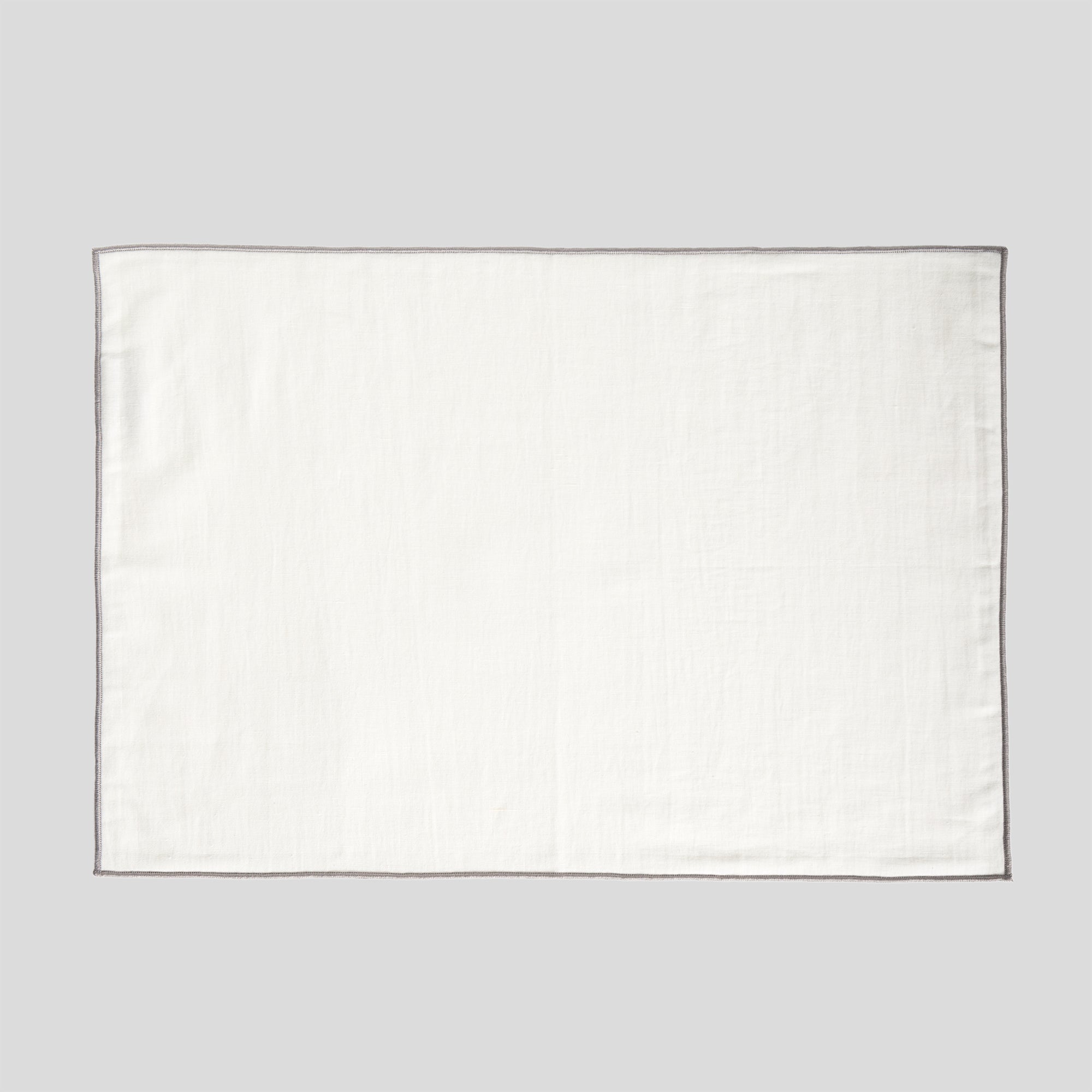 Linen and cotton placemat featuring a smooth surface and grey overlock edge detail.