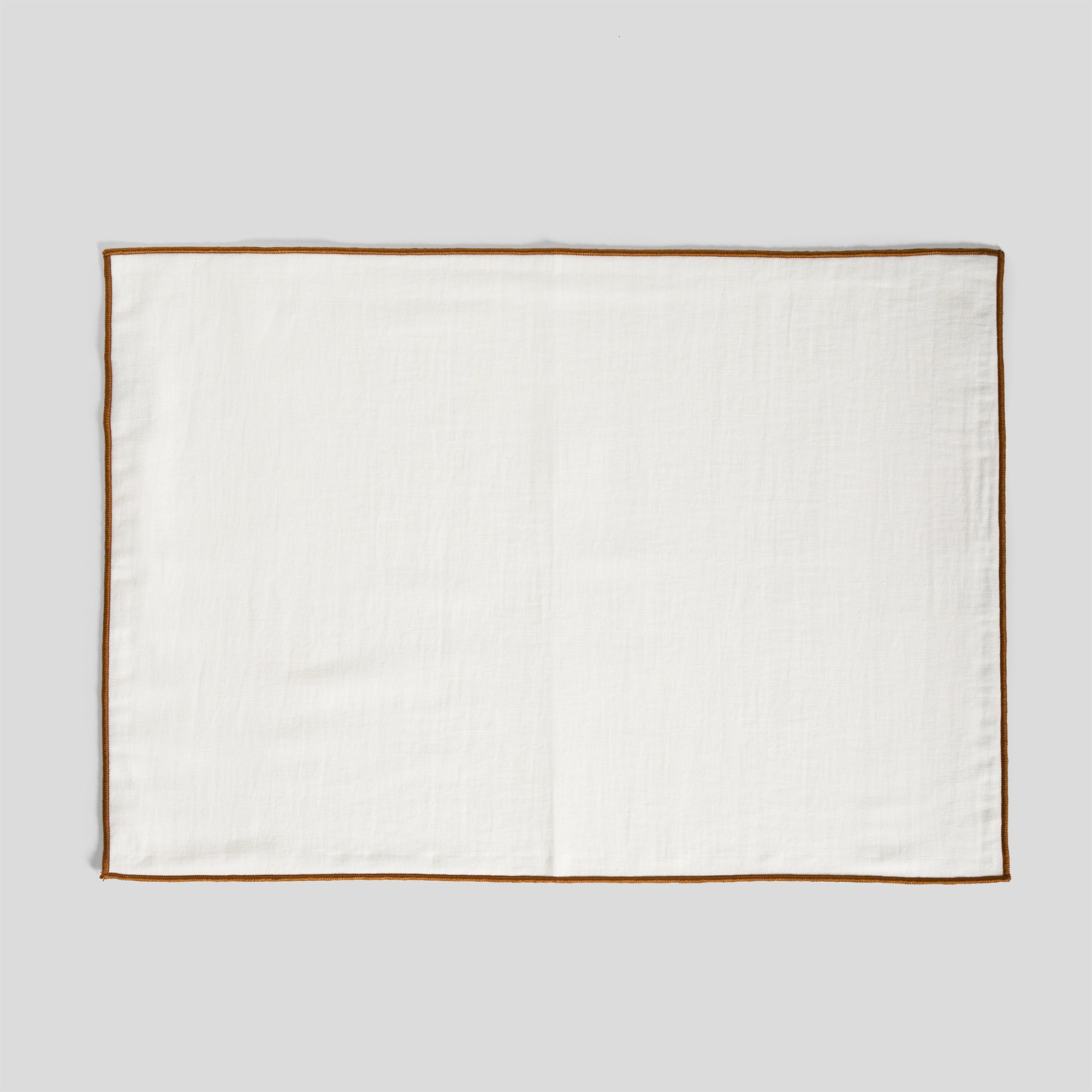 Linen and cotton placemat featuring a smooth surface and amber clay overlock edge detail.