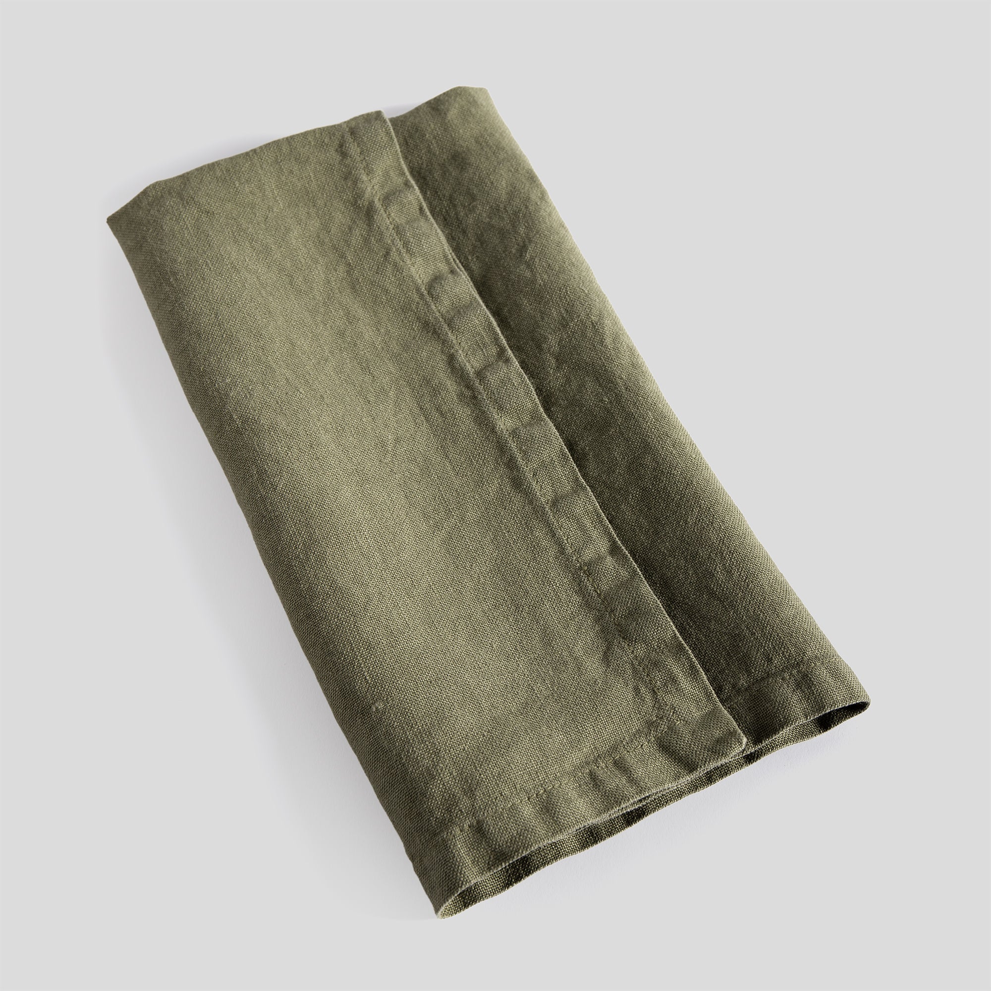 Folded olive linen napkin with refined stitching and a relaxed texture.