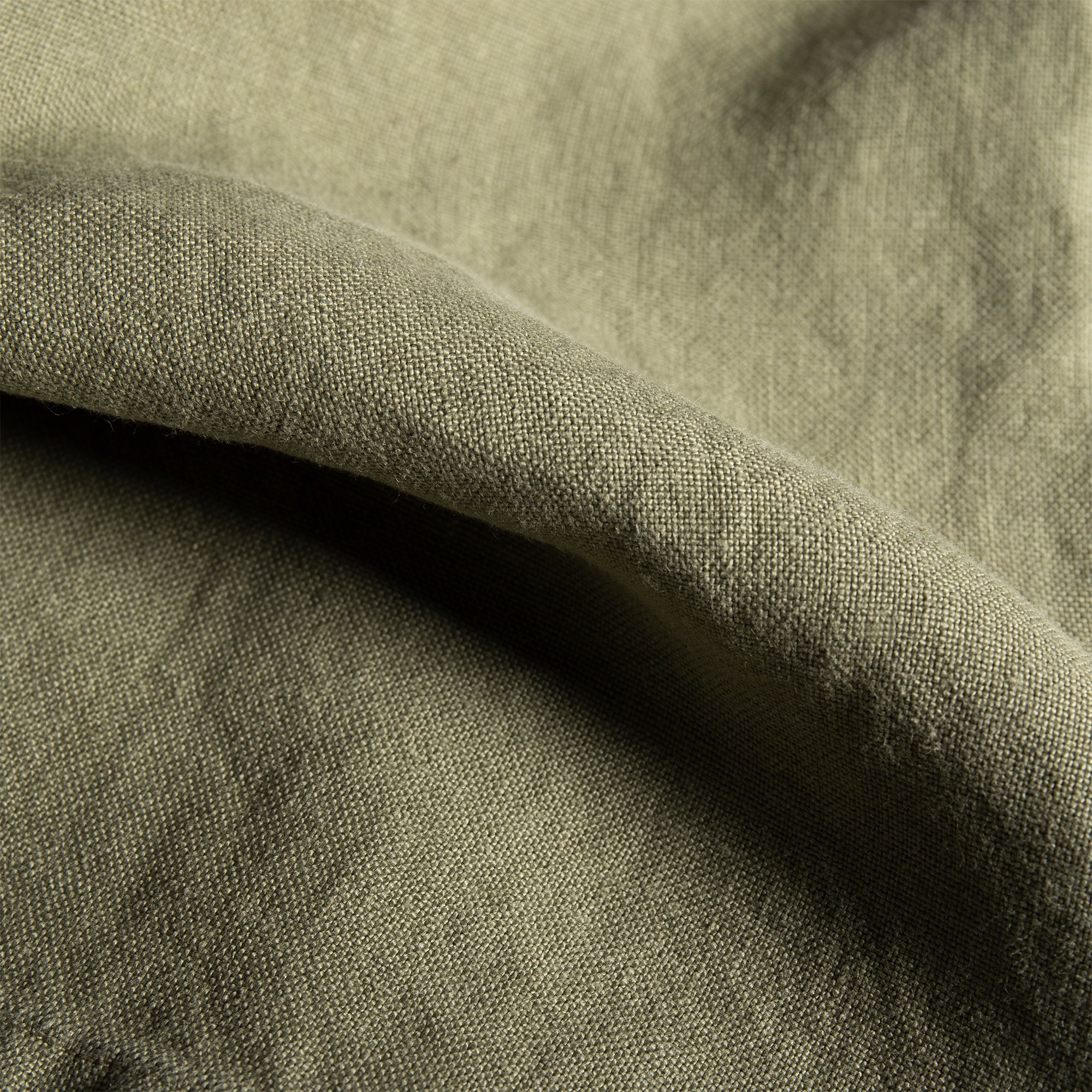 Close-up of olive linen napkin fabric with visible natural texture and soft drape.