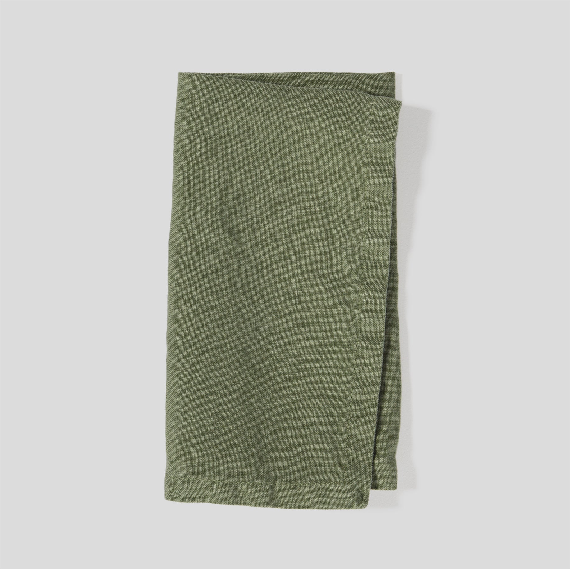Folded heavy linen napkins in olive color with a dense, natural fabric texture.