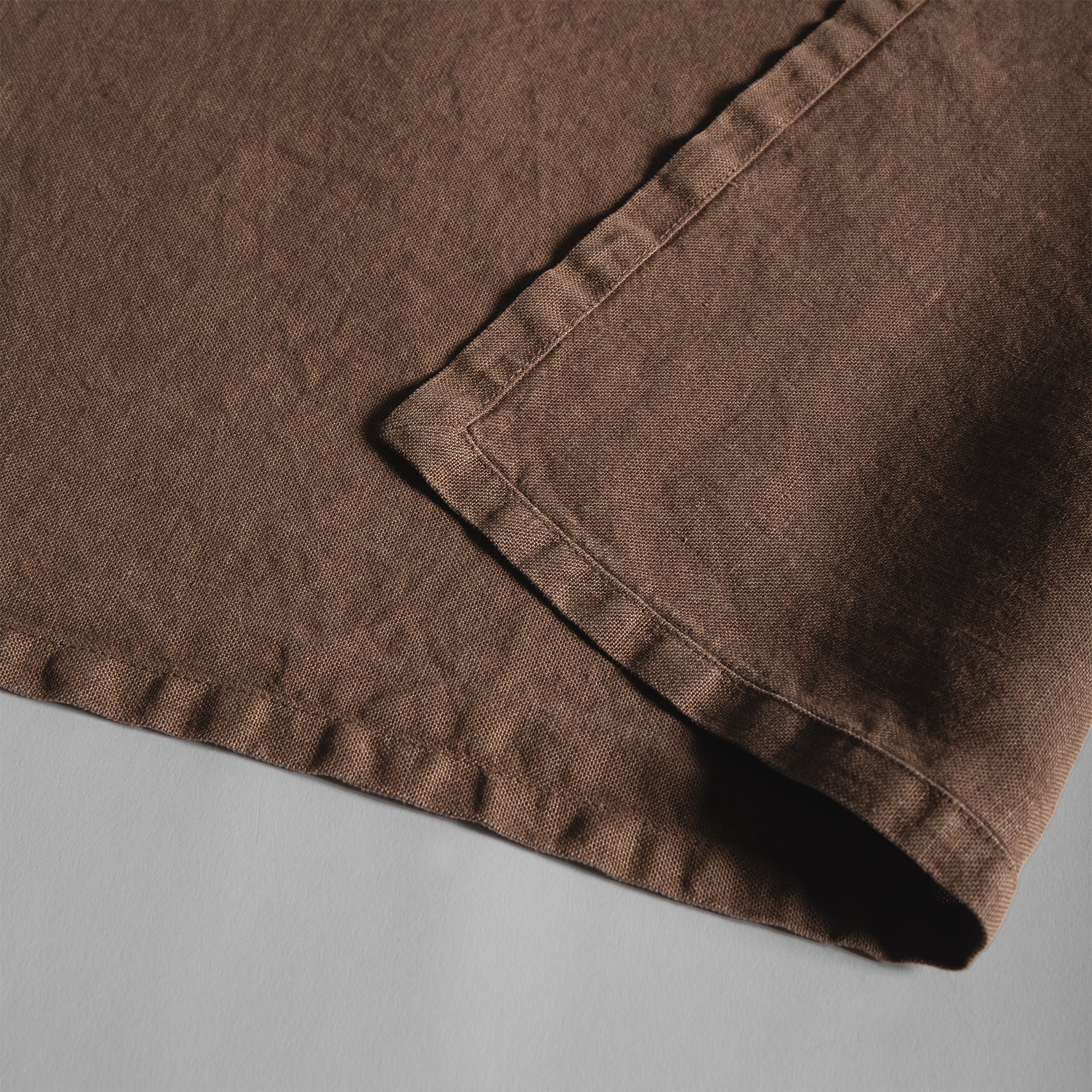 Sable linen placemat with soft texture and relaxed stitched edges.