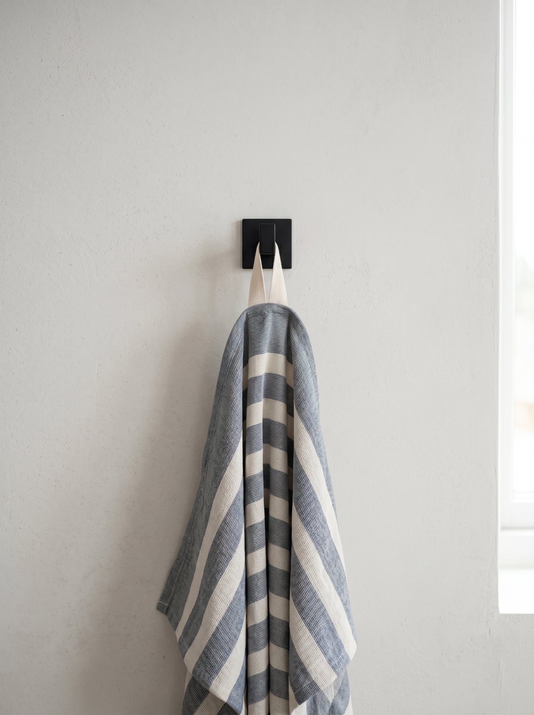 Blue striped 100% cotton kitchen towel hanging from a wall hook, bringing a relaxed and practical touch to the kitchen.