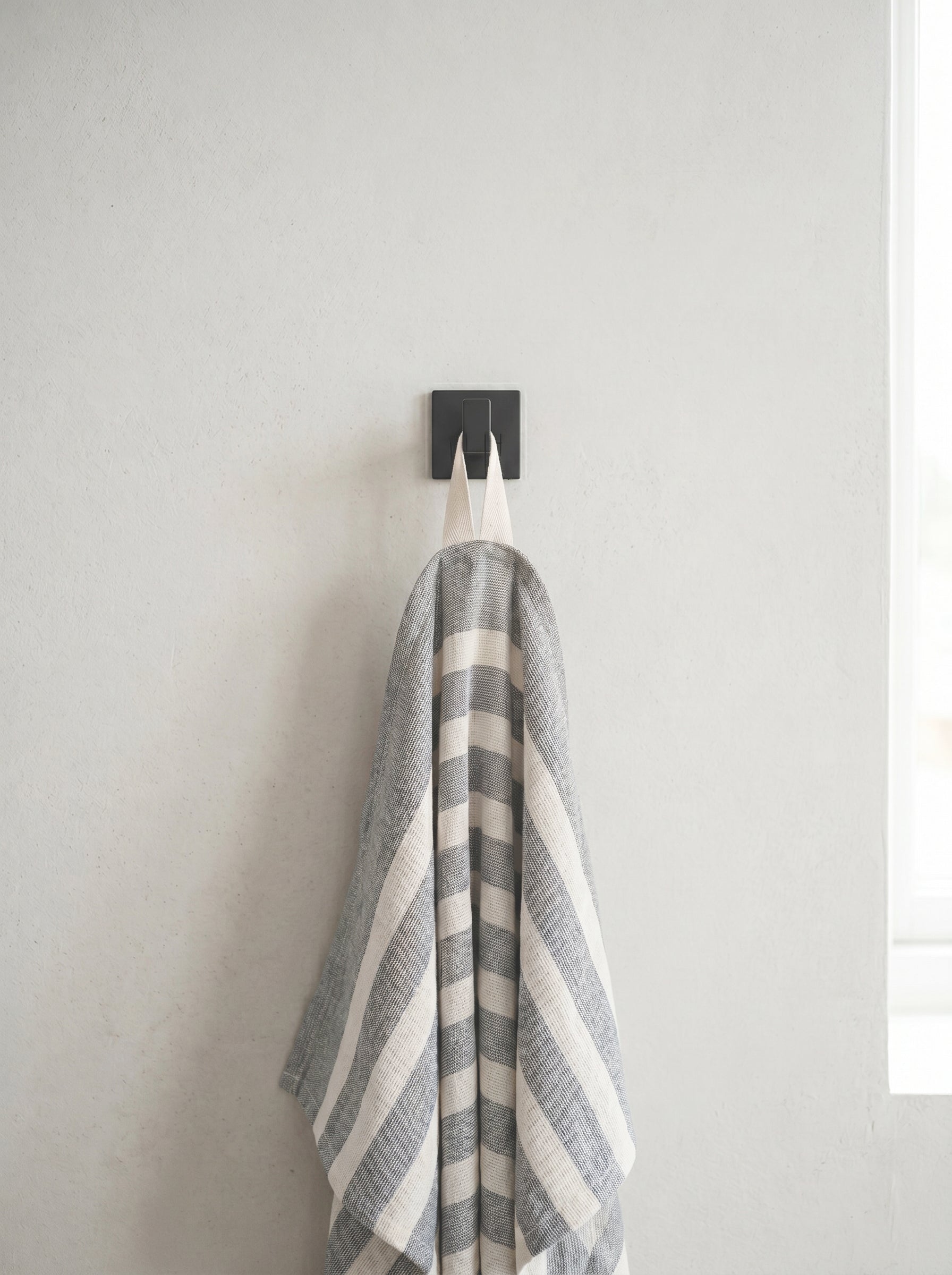 Mist grey striped 100% cotton kitchen towel hanging from a wall hook, bringing a relaxed and practical touch to the kitchen.